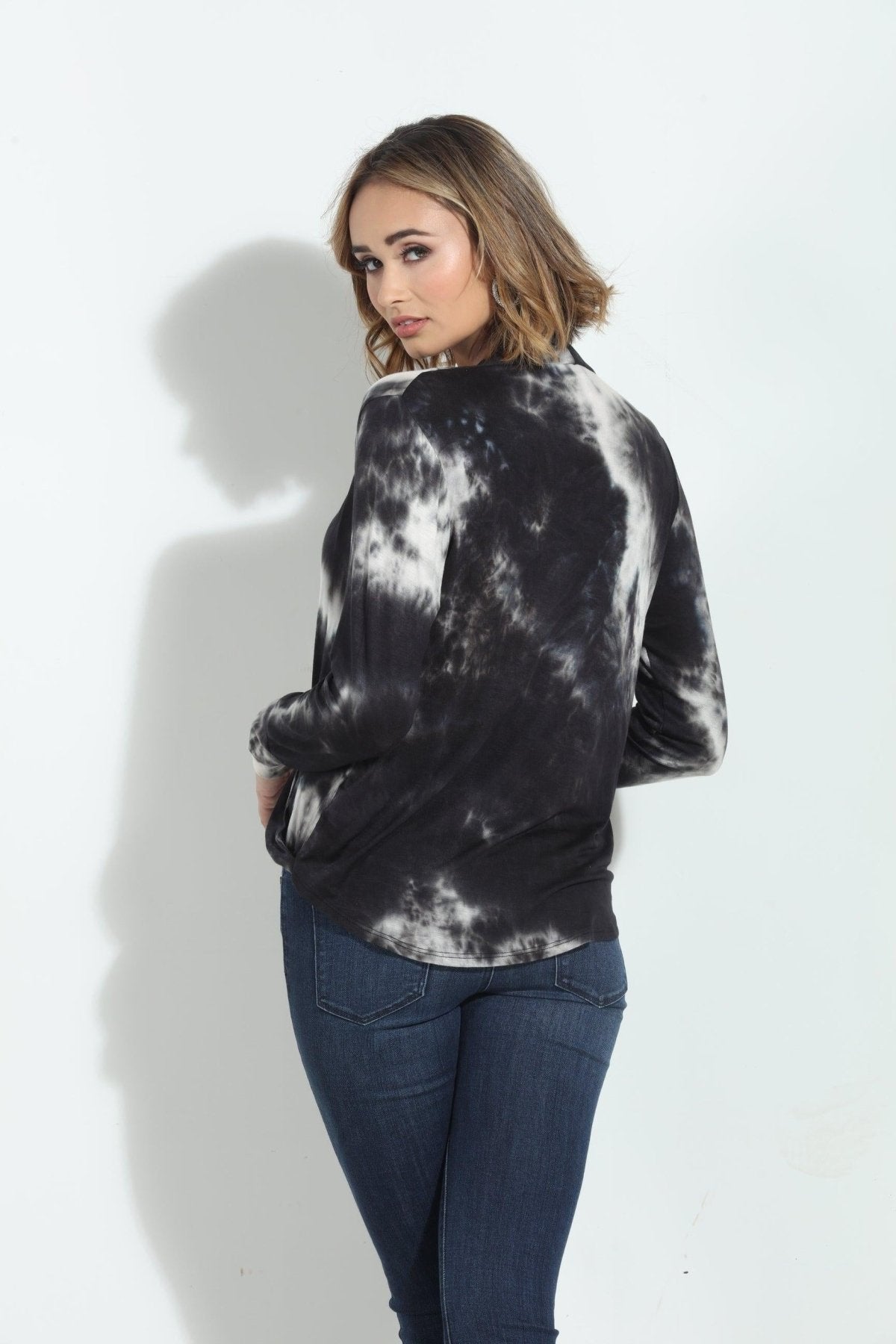 back side of black and white tie-died long sleeve blouse on woman in denim pants