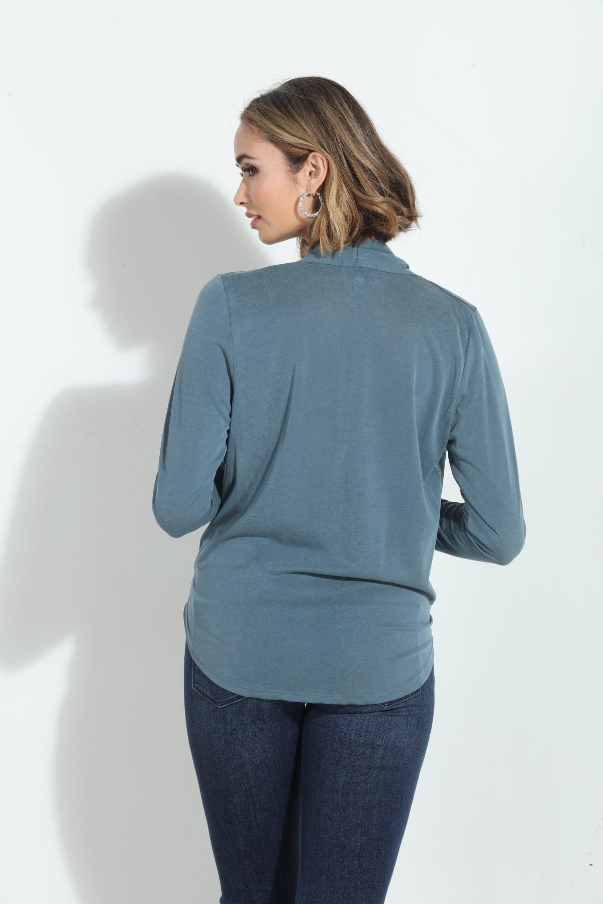 back side of blue long sleeve blouse on woman in denim pants