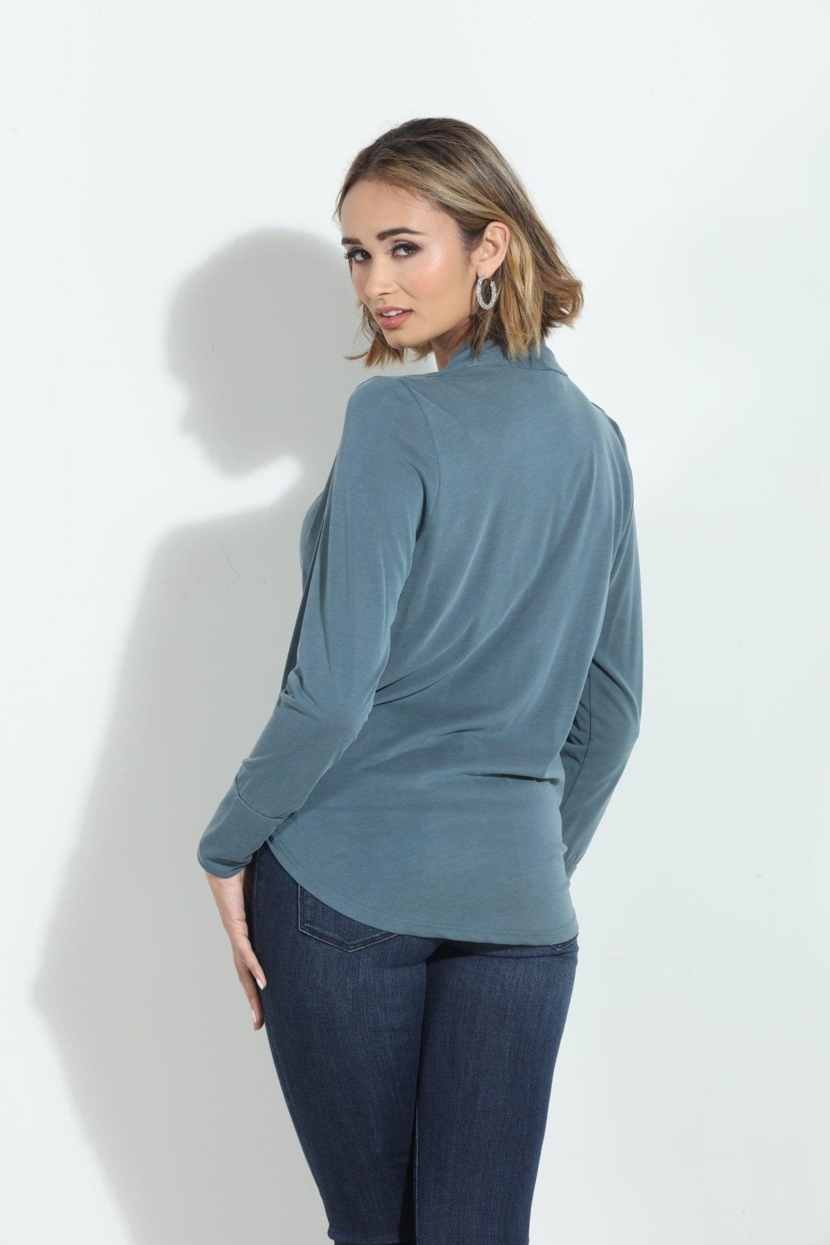 back side of blue long sleeve blouse on woman in denim pants