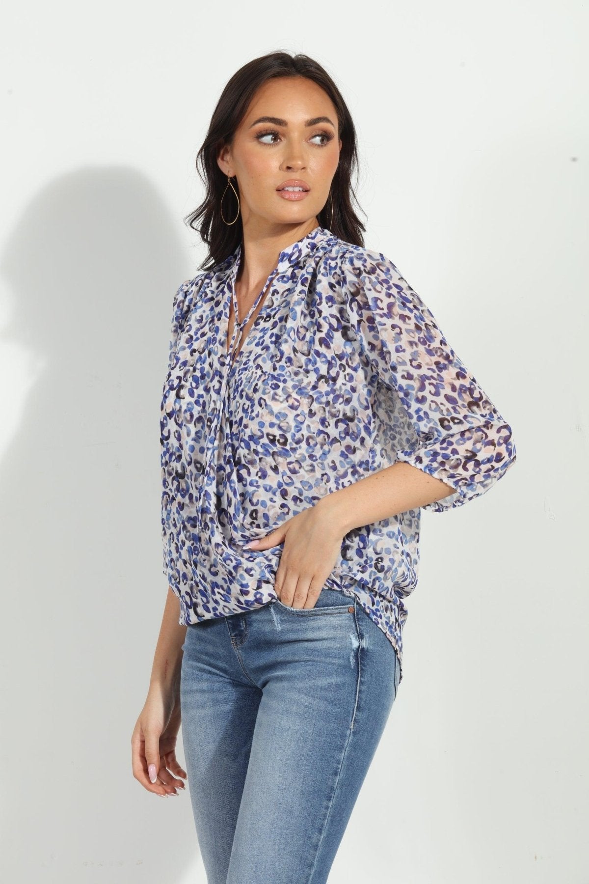blue and white printed long sleeve blouse on woman in denim pants