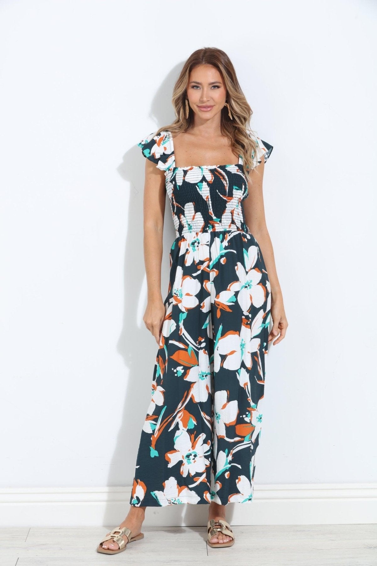 sleeveless floral jumpsuit on woman wearing gold sandals