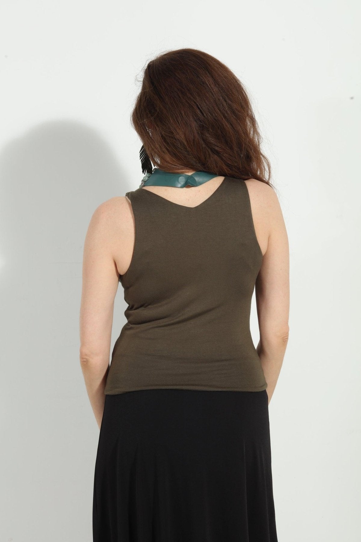 back side of olive green sleeveless top on woman in black skirt
