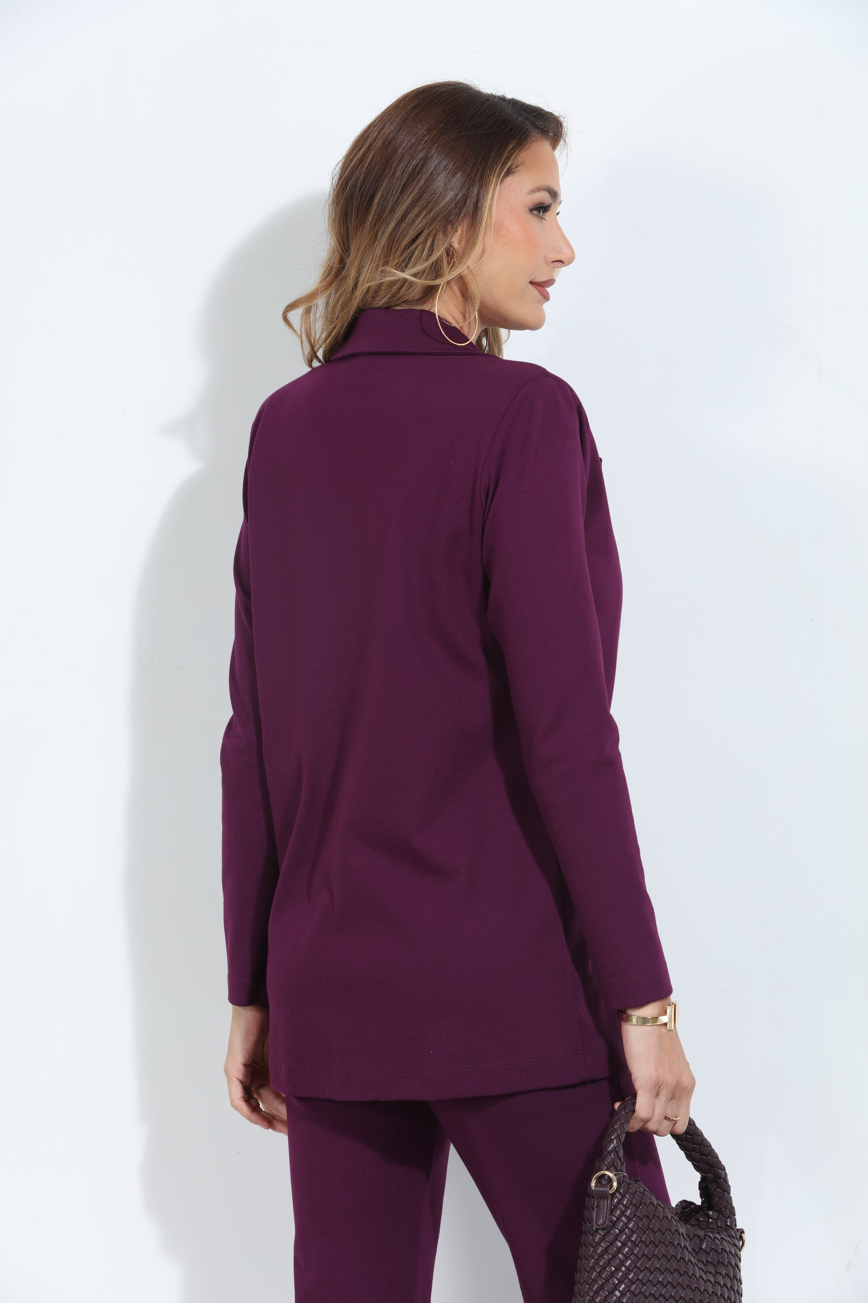 back side of dark purple blazer and pant set on woman holding deep purple purse