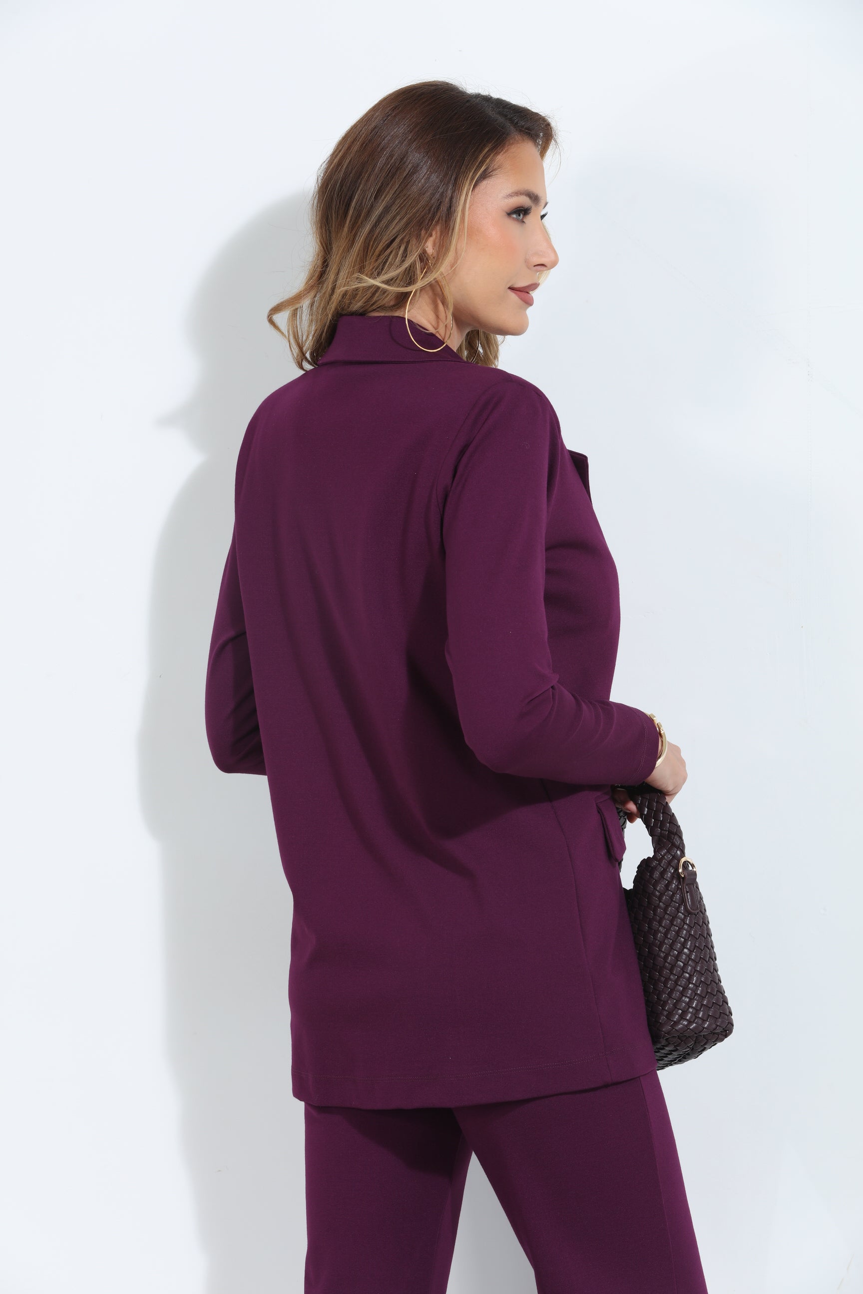 back side of dark purple blazer and pant set on woman holding deep purple purse