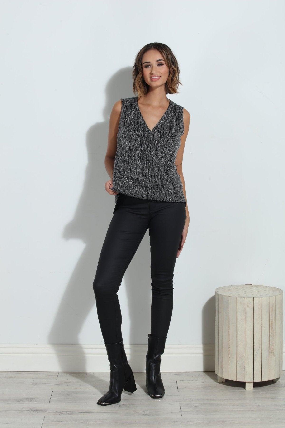 silver sparkle sleeveless blouse on woman in black pants and black boots