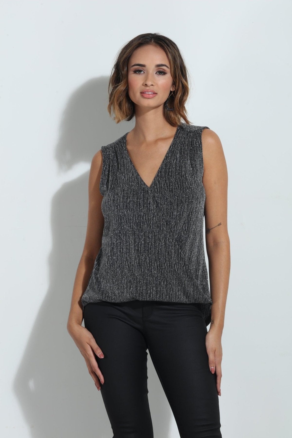 silver sparkle sleeveless blouse on woman in black pants