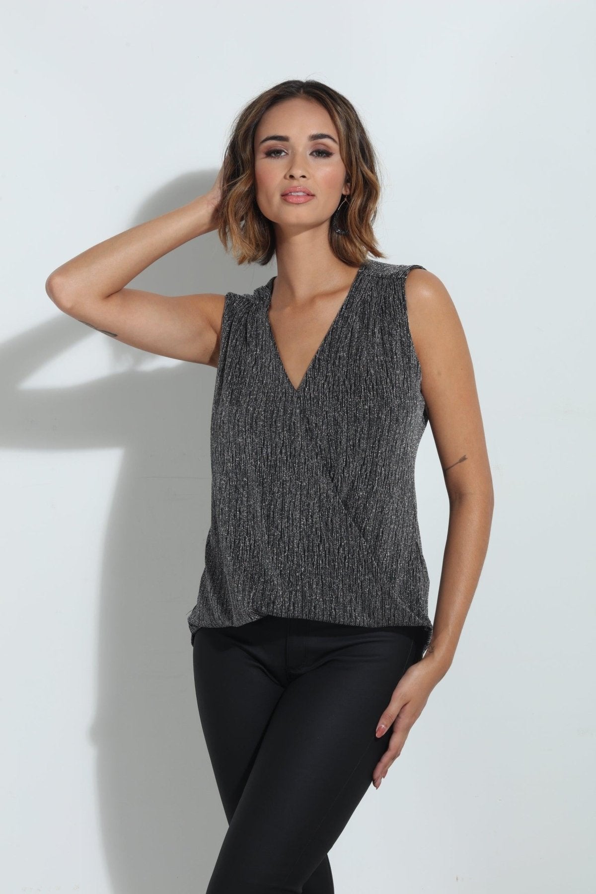 silver sparkle sleeveless blouse on woman in black pants
