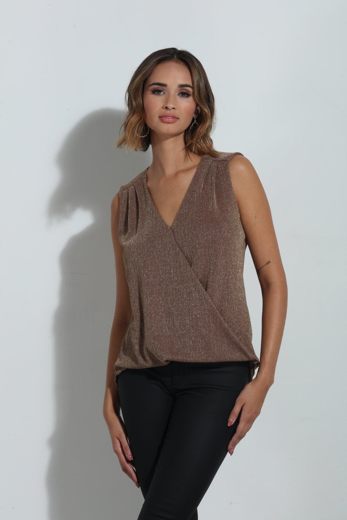 brown sparkle sleeveless blouse on woman in black pants