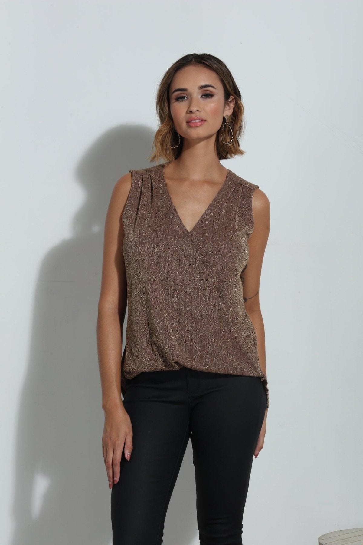 brown sparkle sleeveless blouse on woman in black pants