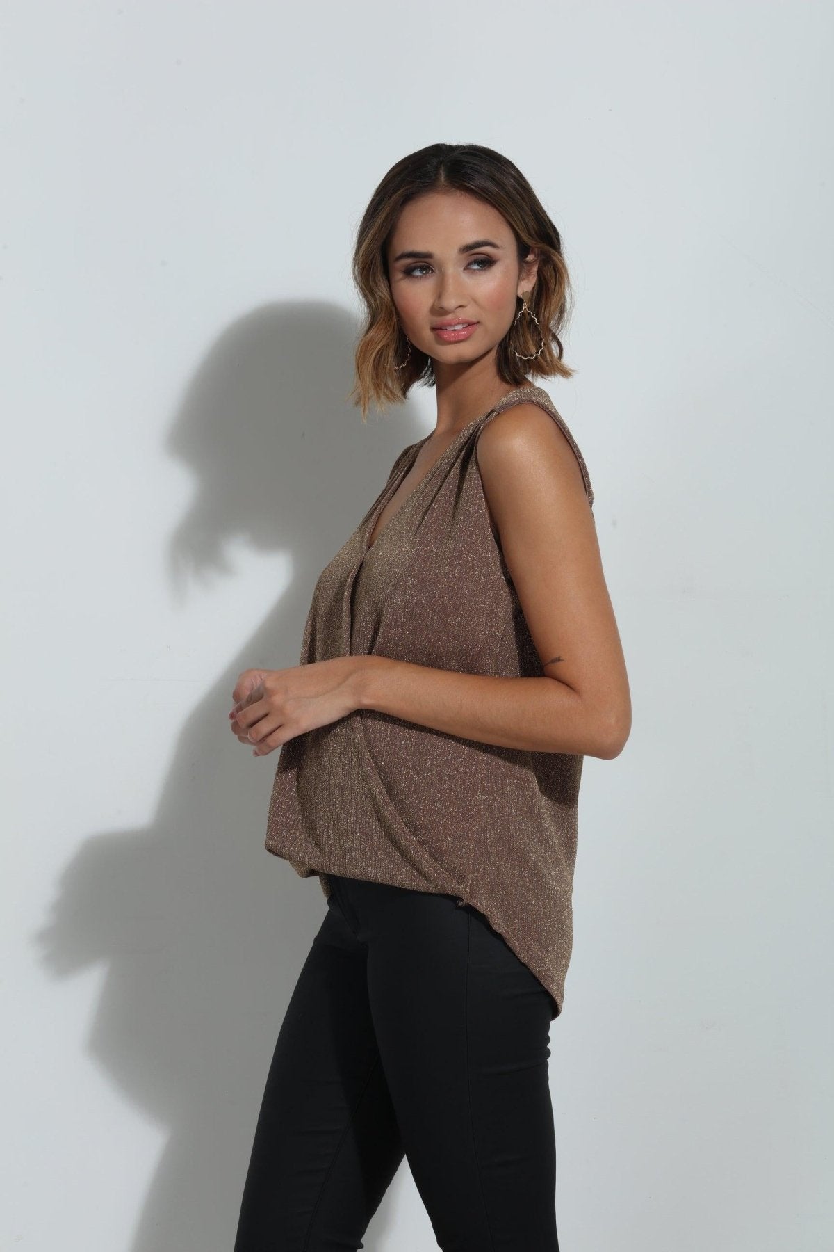 brown sparkle sleeveless blouse on woman in black pants