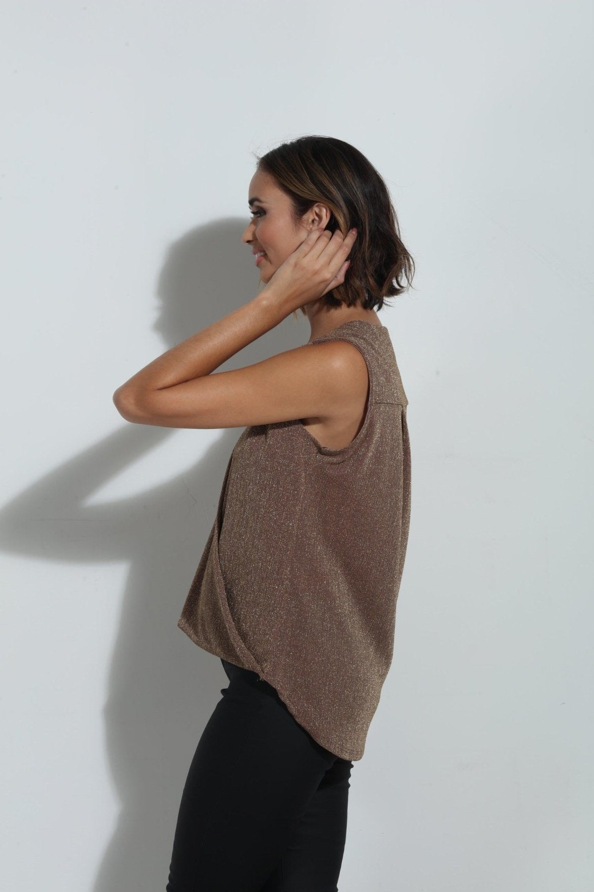 side angle of brown sparkle sleeveless blouse on woman in black pants