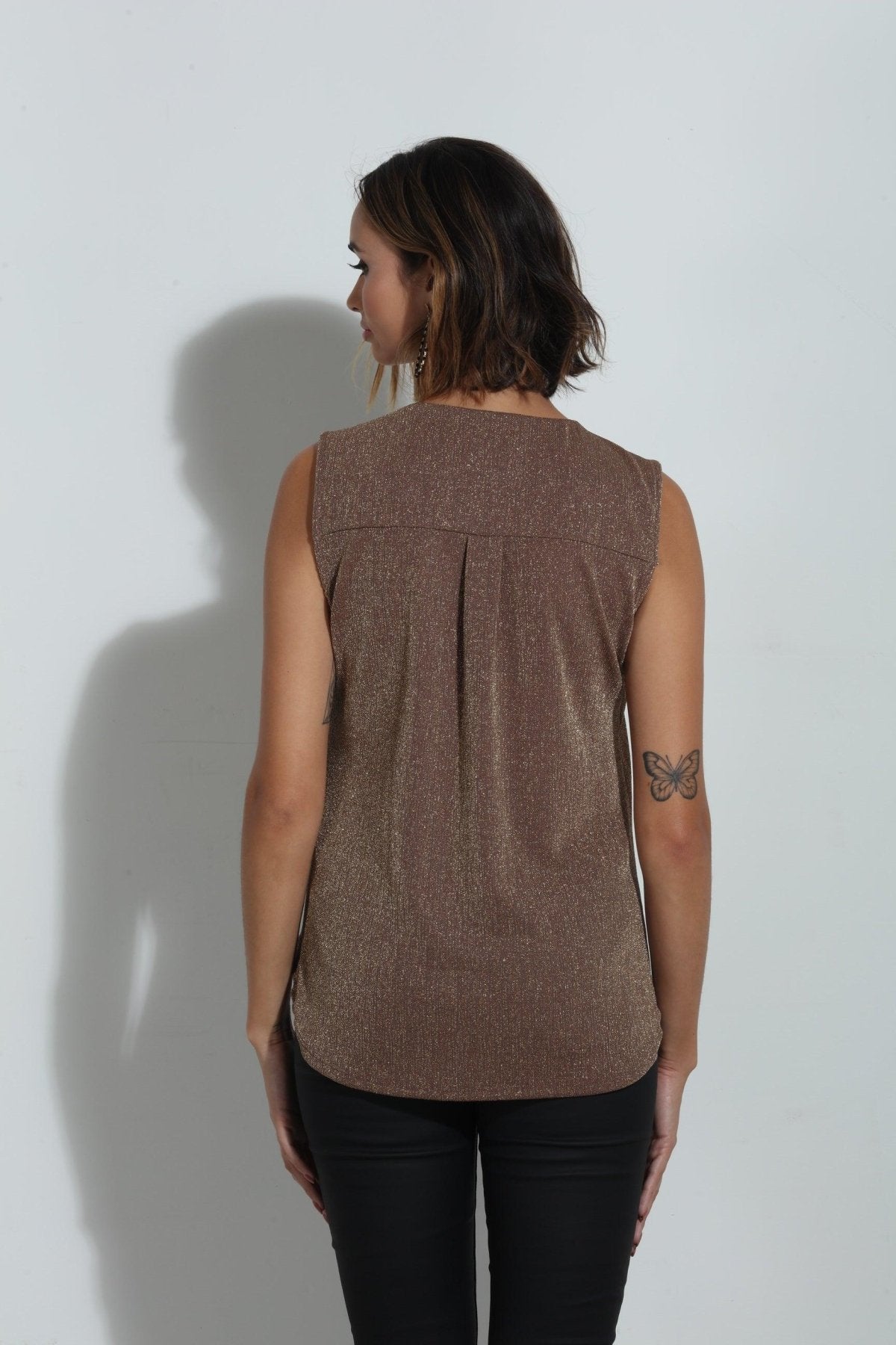 back side of brown sparkle sleeveless blouse on woman in black pants