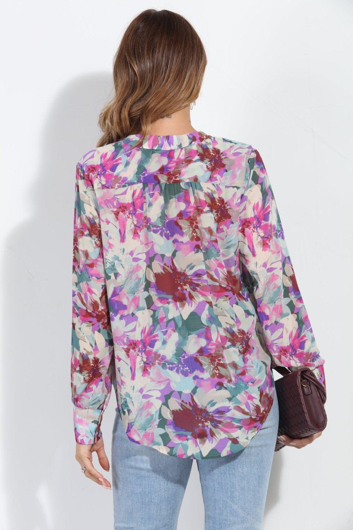 back side of floral multicolored blouse on woman in jeans and holding dark purple blouse