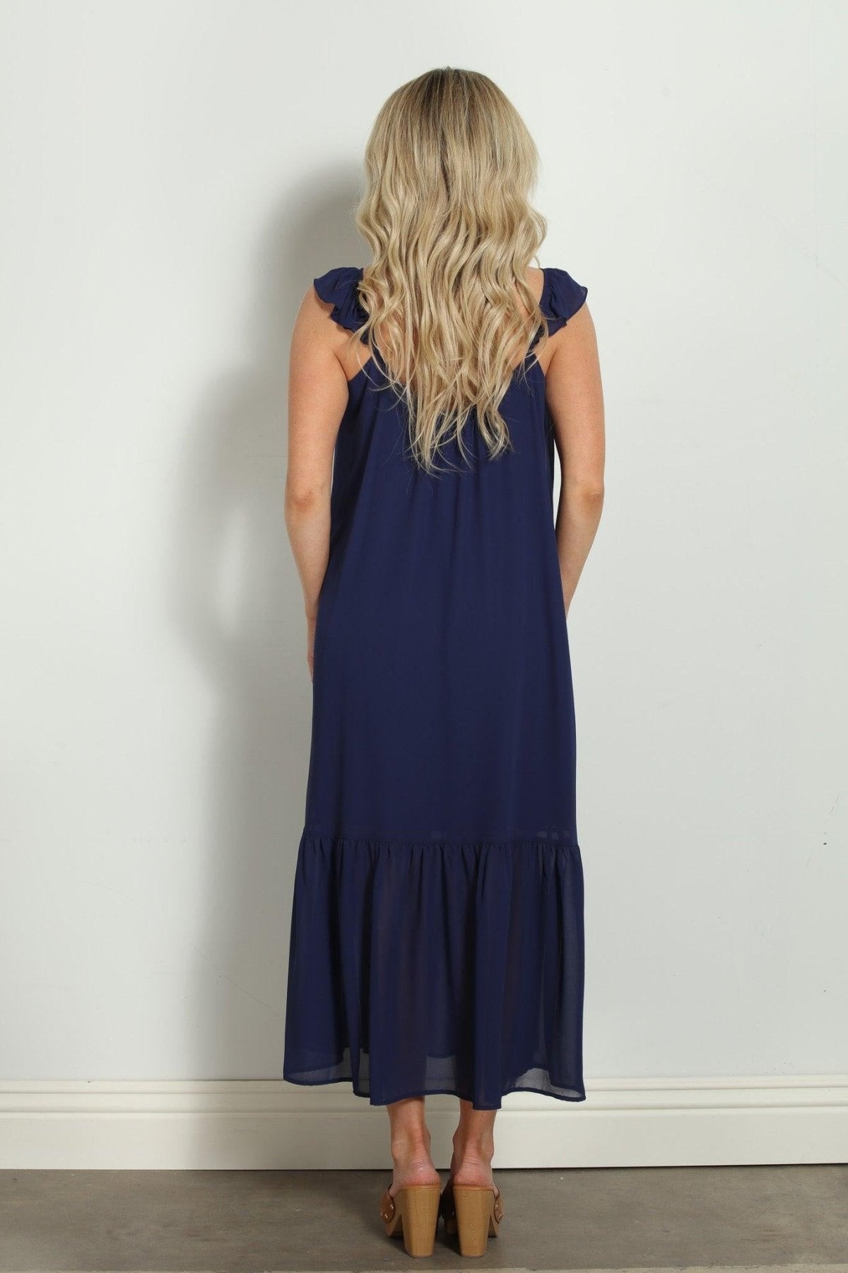 backside of woman in sleeveless navy maxi dress