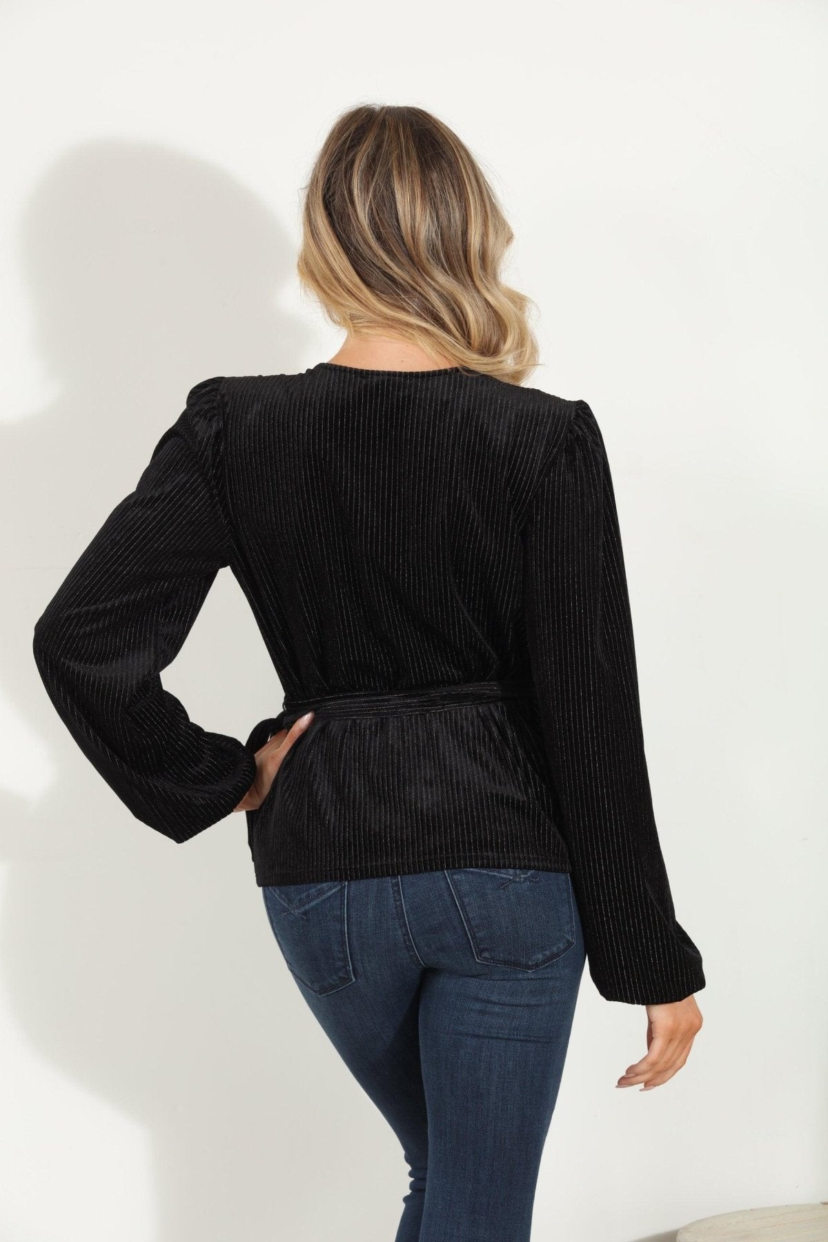 backside of woman in a black velvet wrap top and jeans