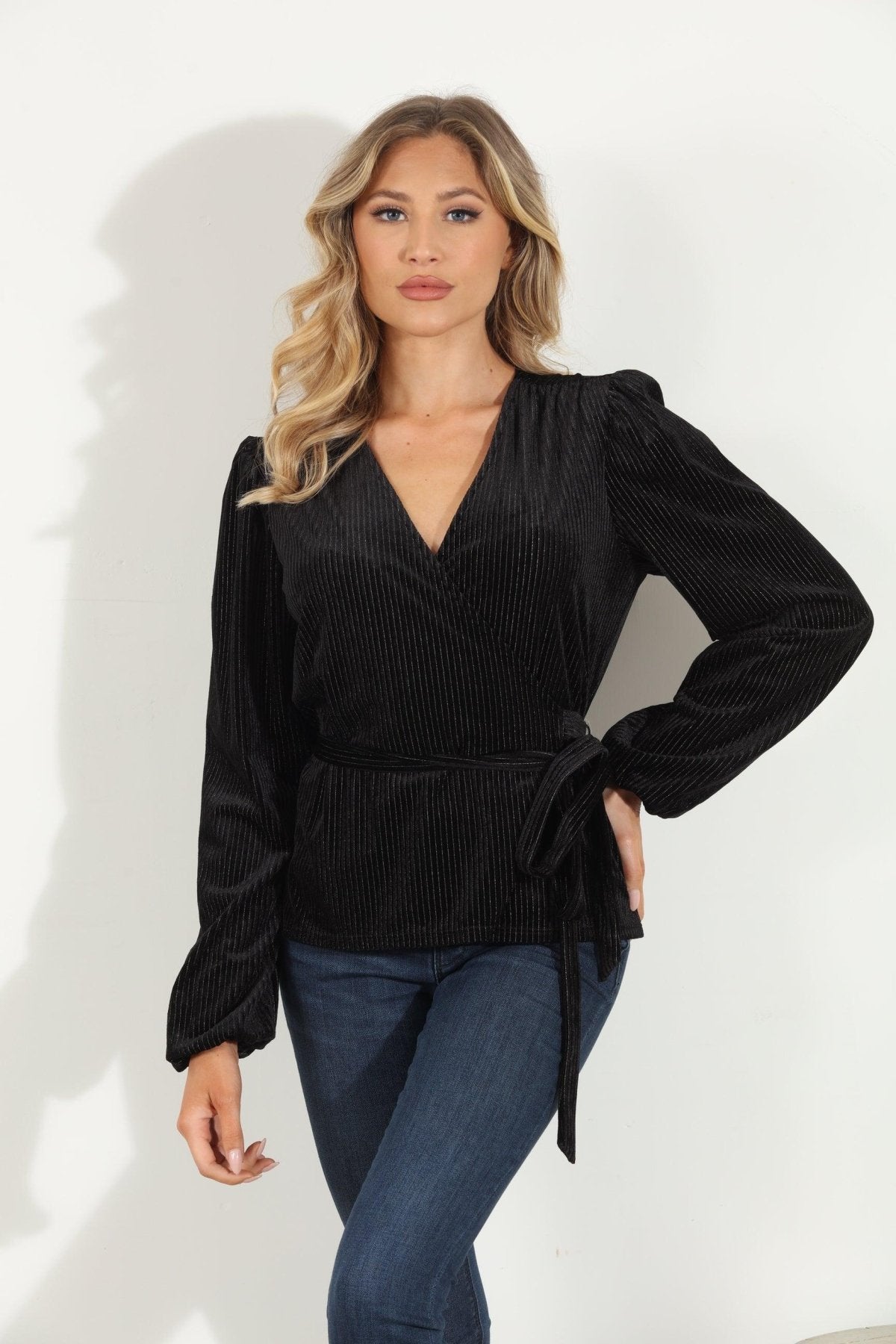 woman in a black velvet wrap top and jeans