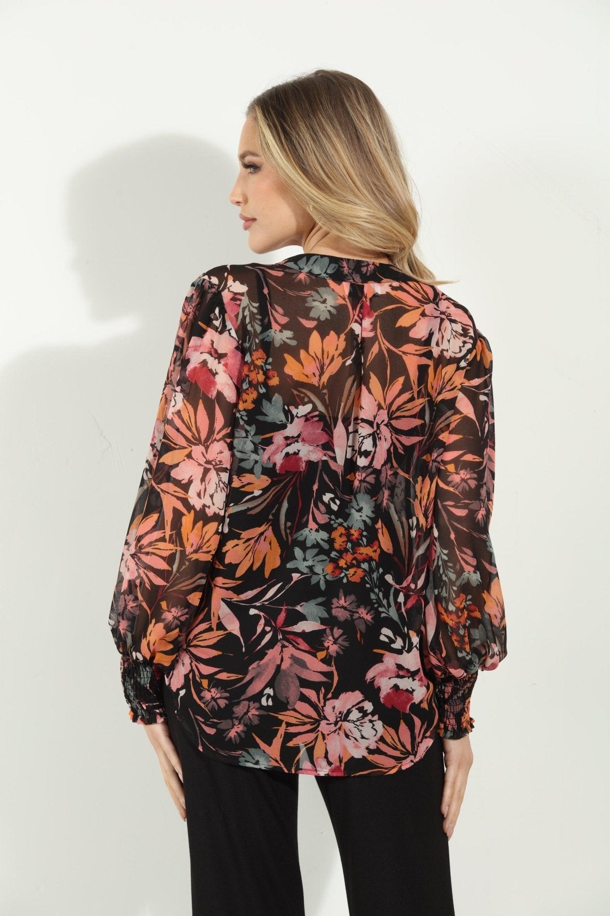 backside of multicolored long sleeve floral blouse on woman in black pants