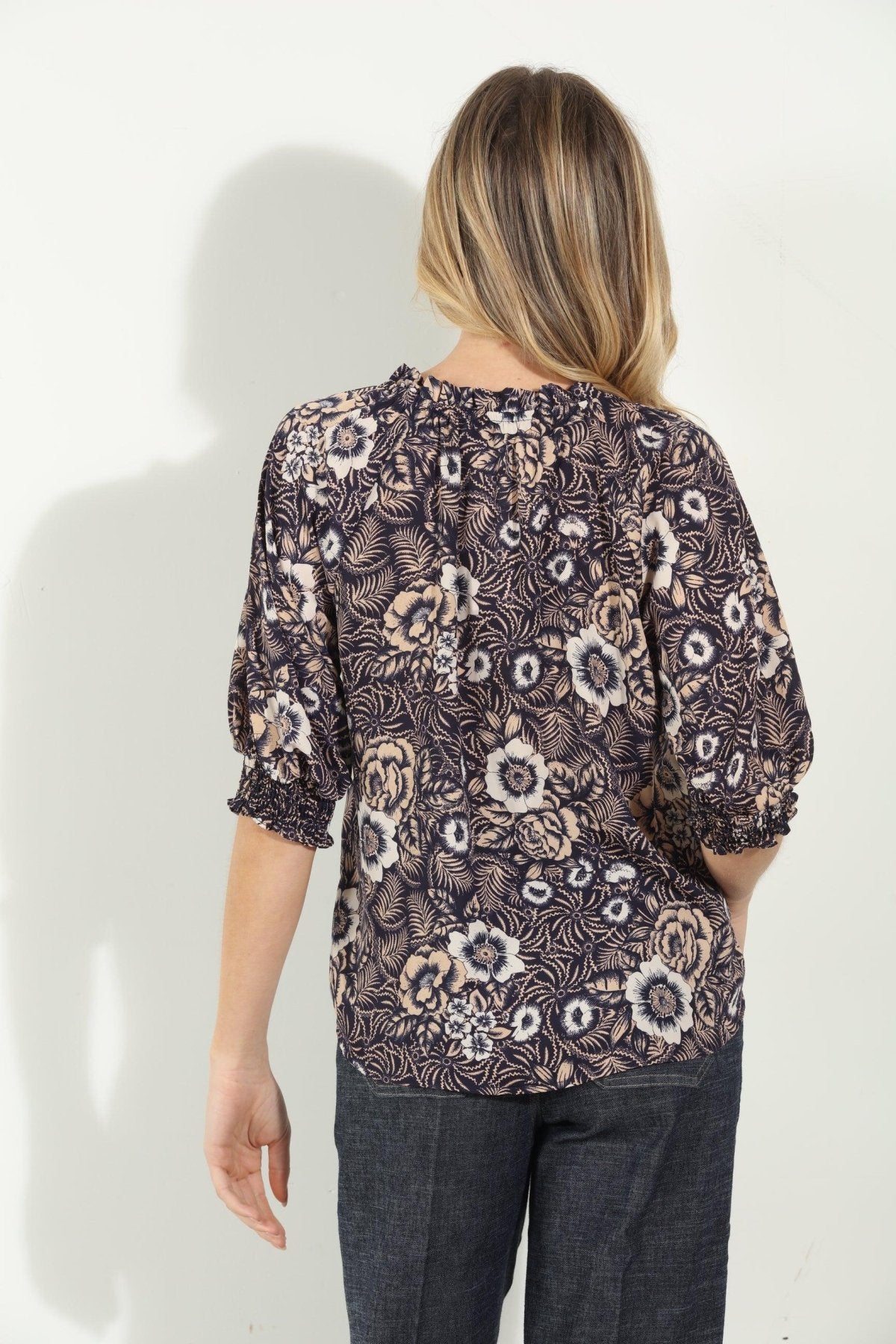 backside of woman in multicolored short sleeve blouse and denim