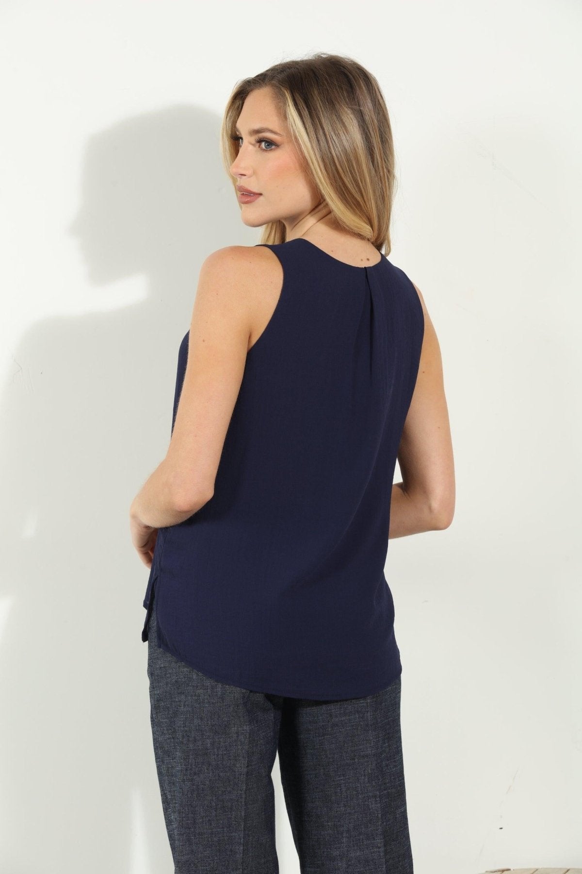 backside of navy sleeveless blouse on woman in denim pants