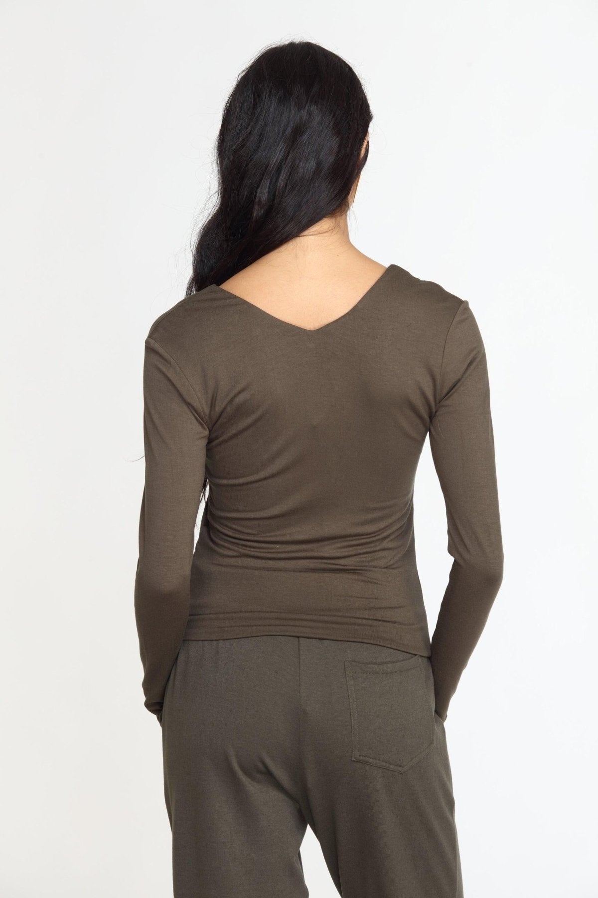 back side of olive long sleeve vneck top on woman in olive pants