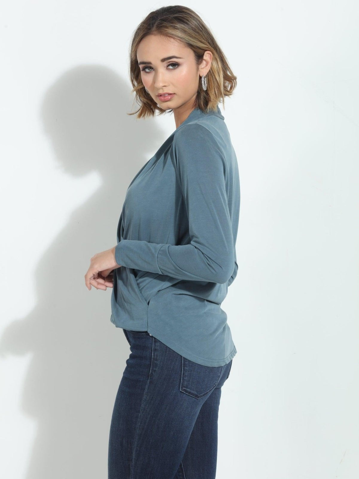 side angle of blue long sleeve blouse on woman in denim pants