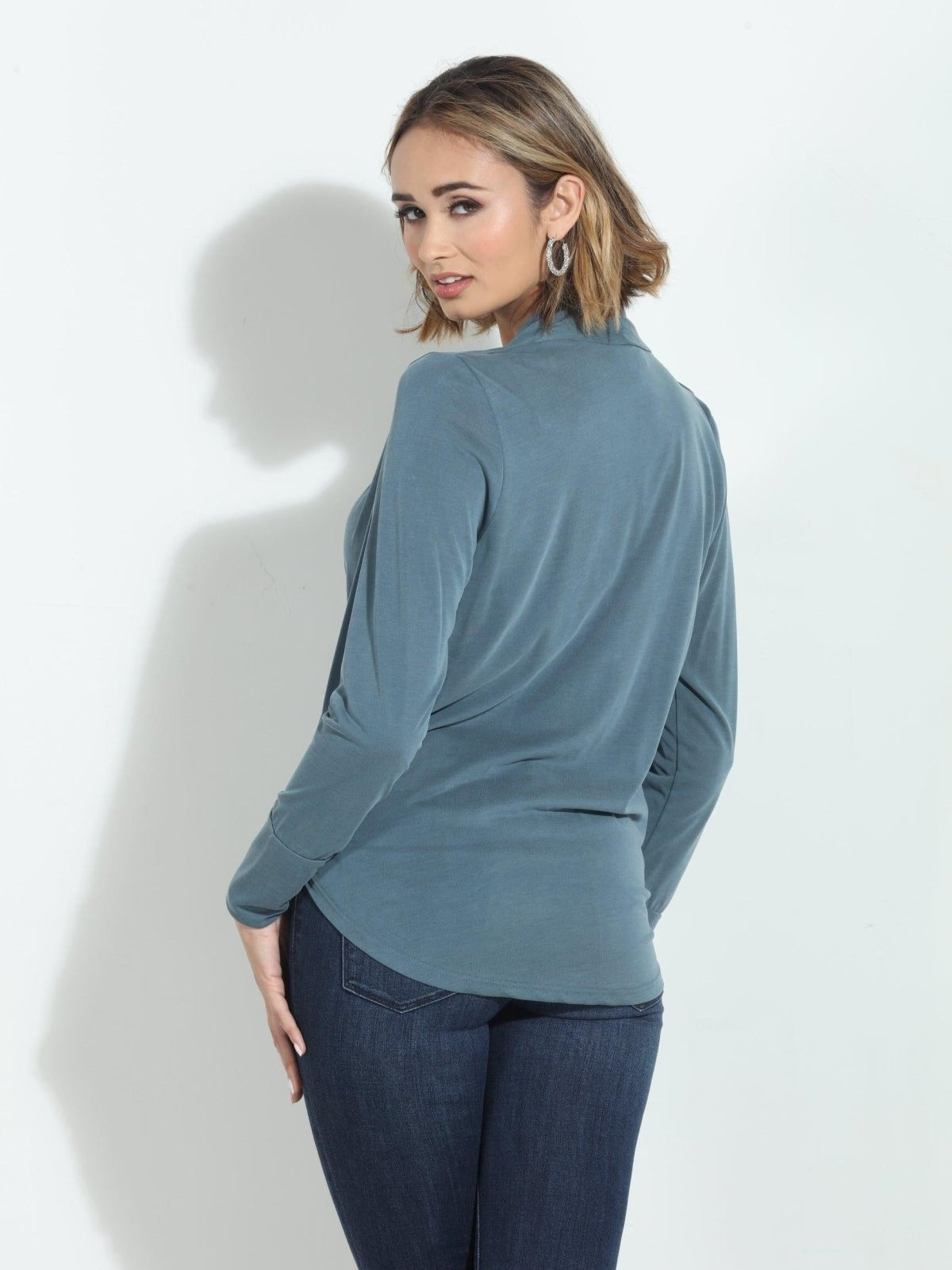 back side of blue long sleeve blouse on woman in denim pants