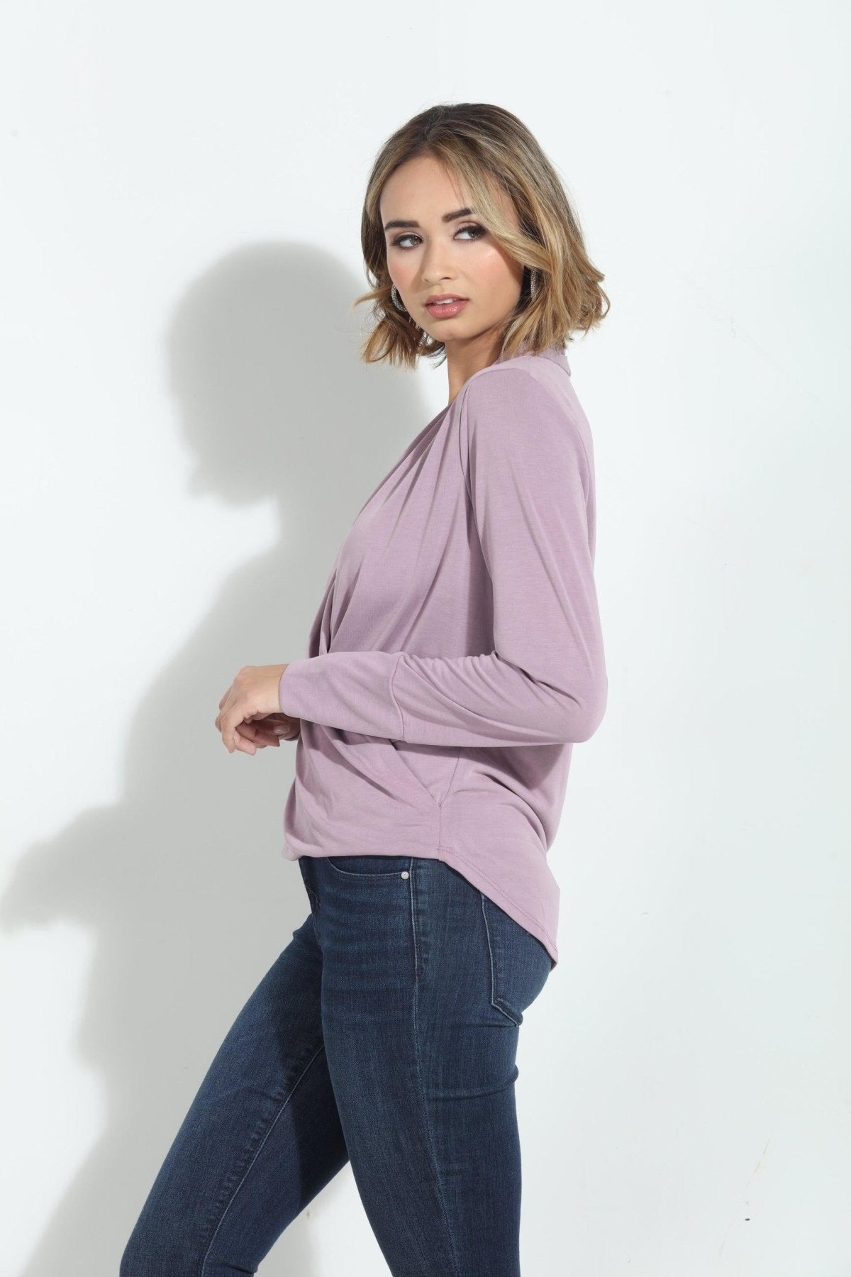 side angle of pink long sleeve blouse on woman in denim pants