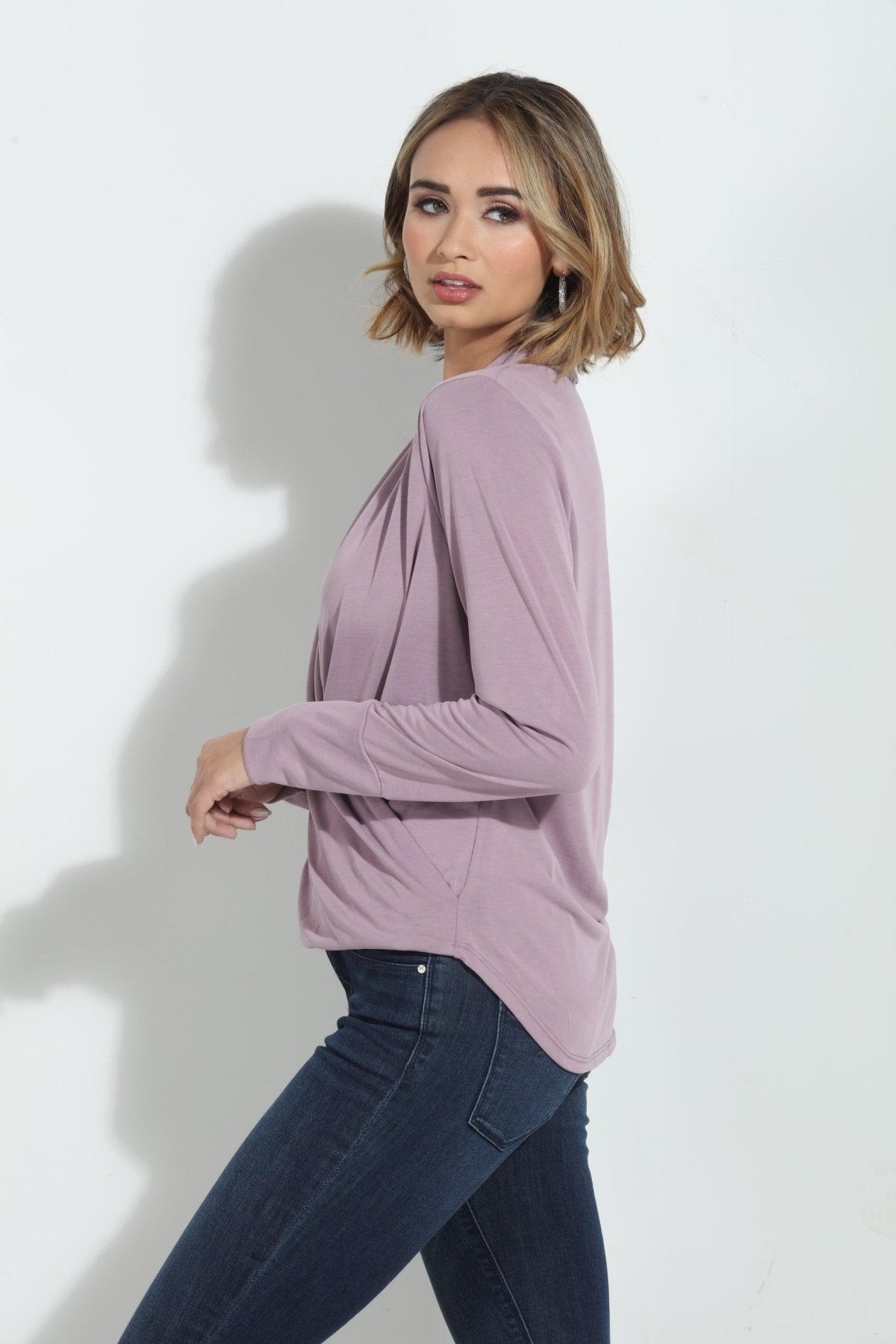 size angle of pink long sleeve blouse on woman in denim pants