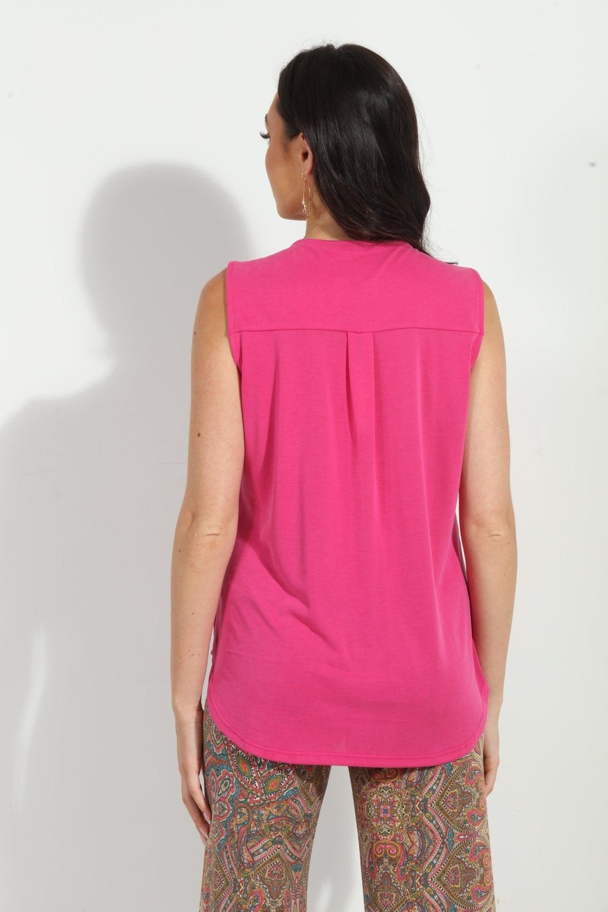 back side of hot pink sleeveless top on woman in multicolored pants