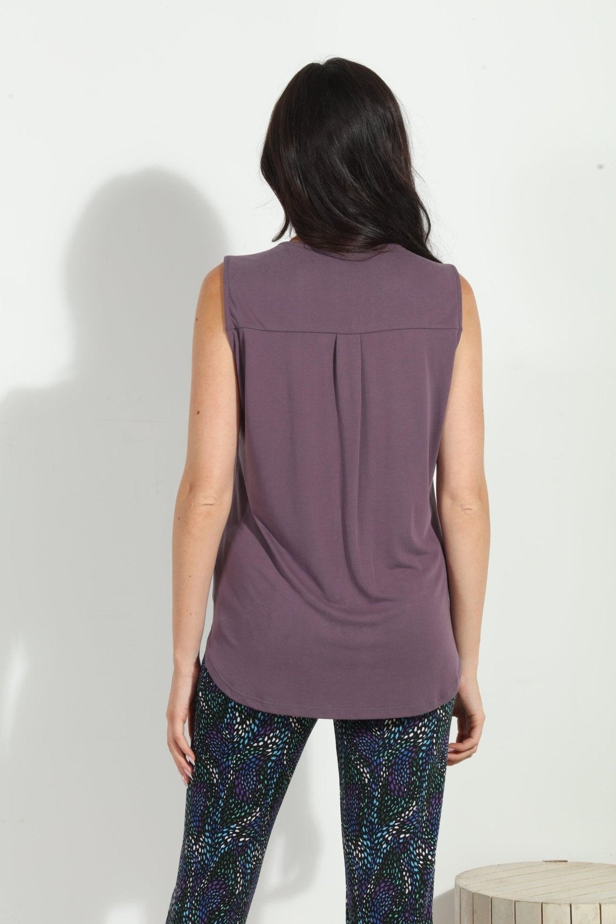 back side of dark purple sleeveless top on woman in multicolored pants