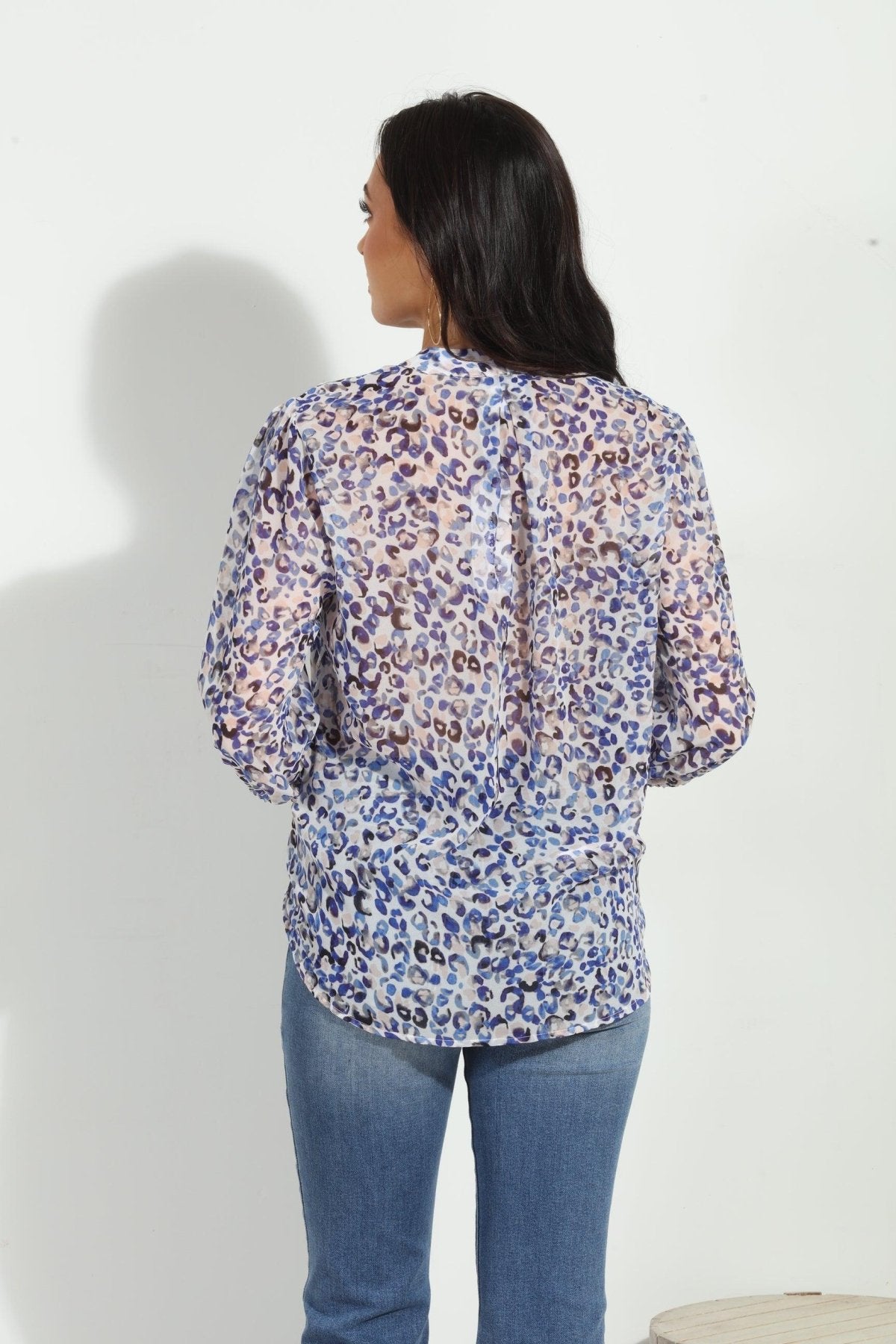 back side of blue and white printed long sleeve blouse on woman in denim pants