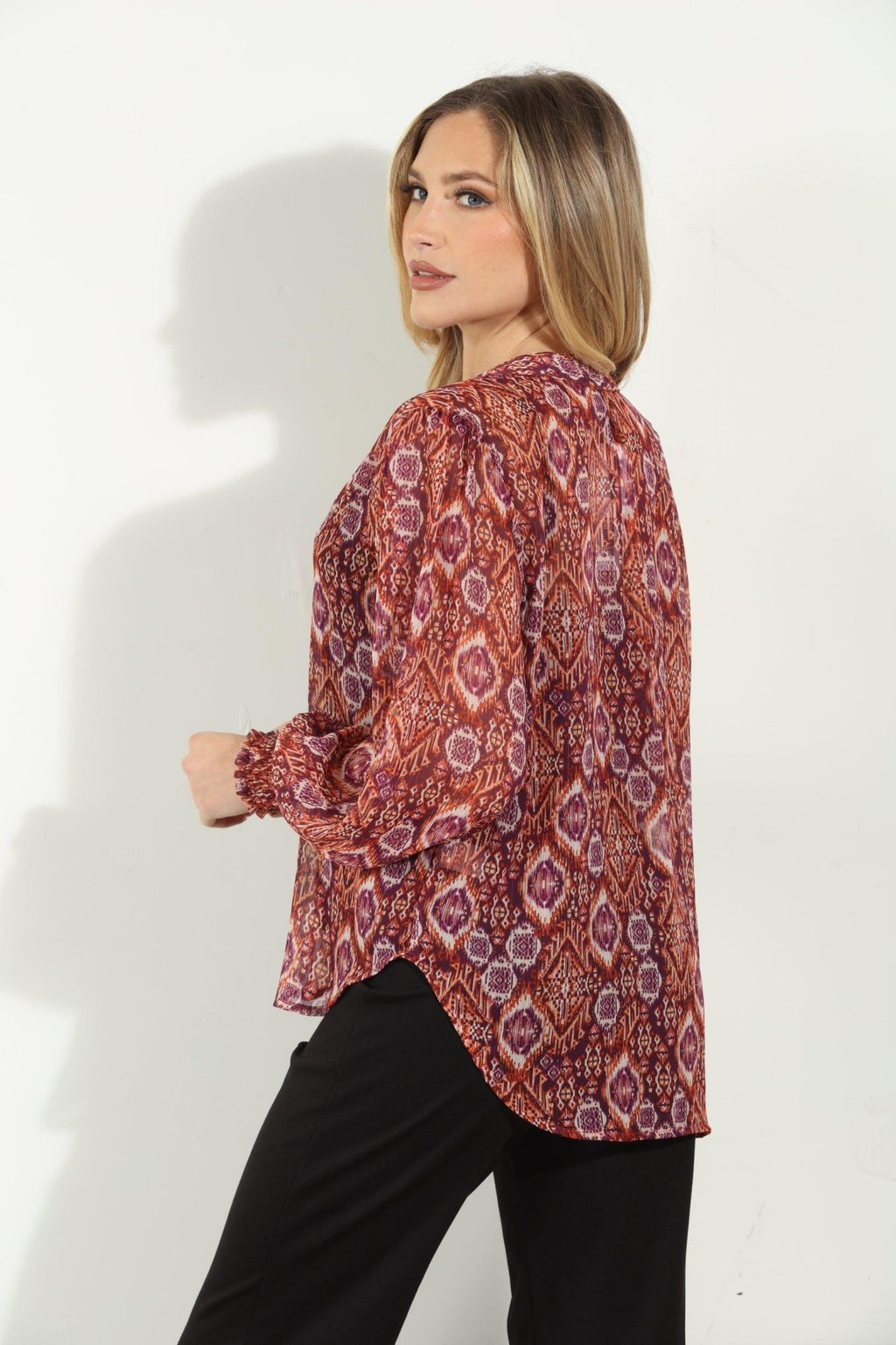 backside of woman in printed long-sleeve blouse and black pants