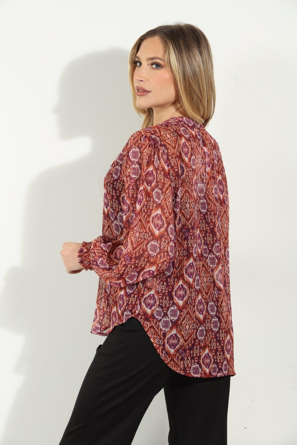 backside of woman in printed long-sleeve blouse and black pants