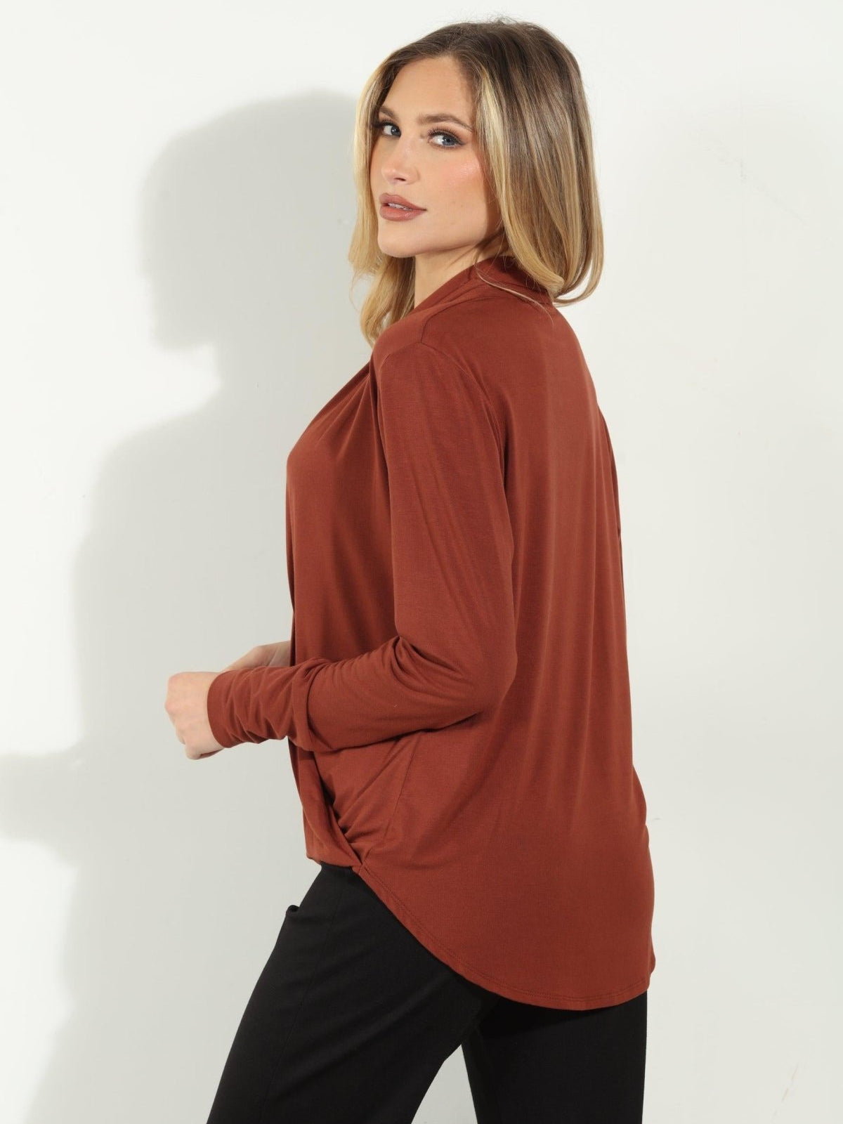 back side of dark orange long sleeve blouse on woman in black pants
