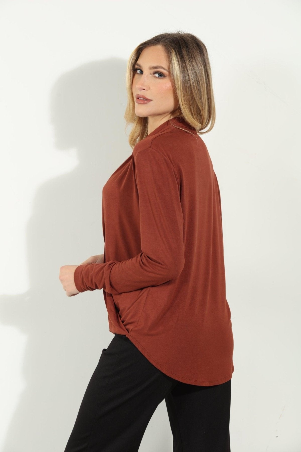 back side of dark orange long sleeve blouse on woman in black pants