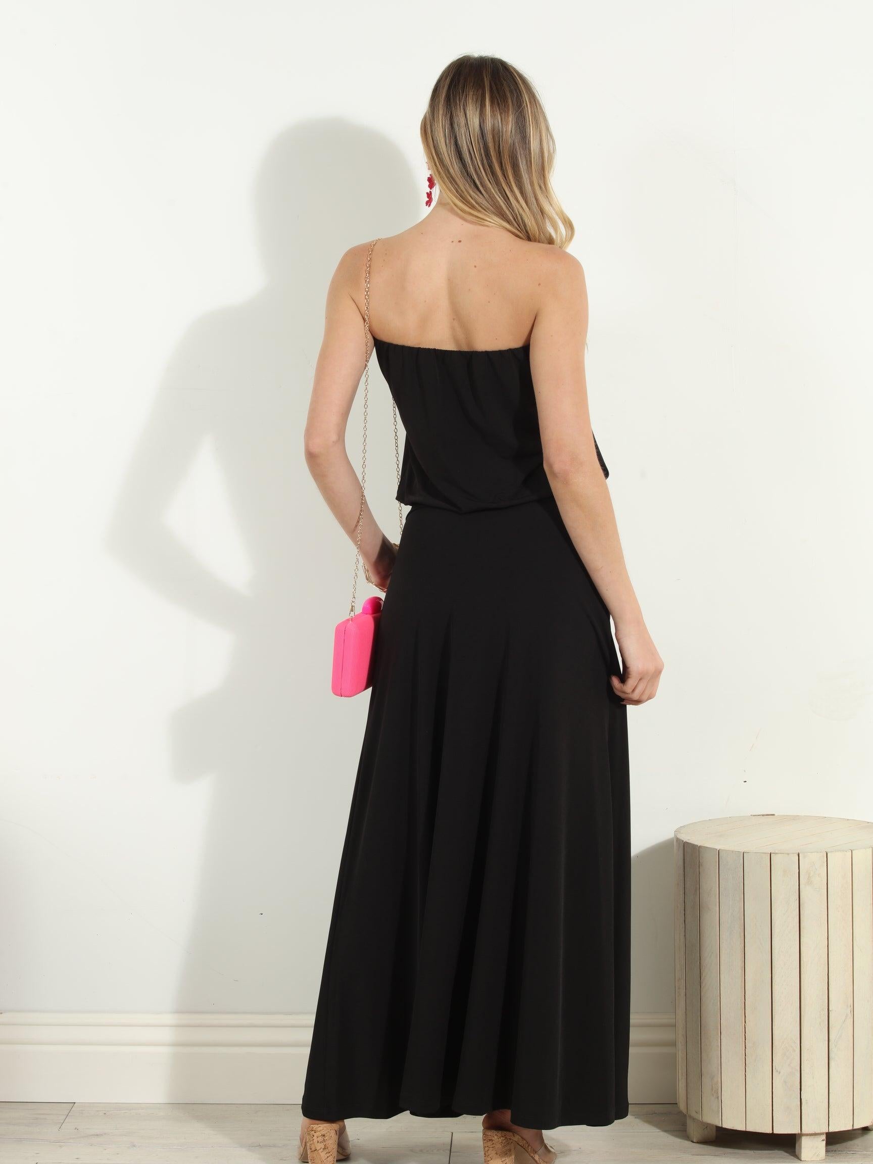 back side of black strapless maxi dress on woman holding pink purse