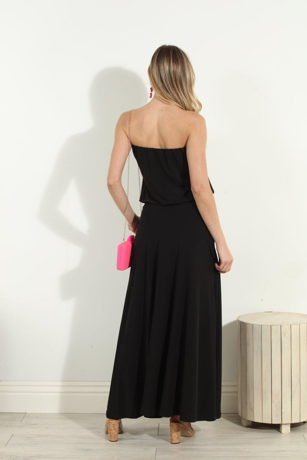 back side of black strapless maxi dress on woman holding pink purse