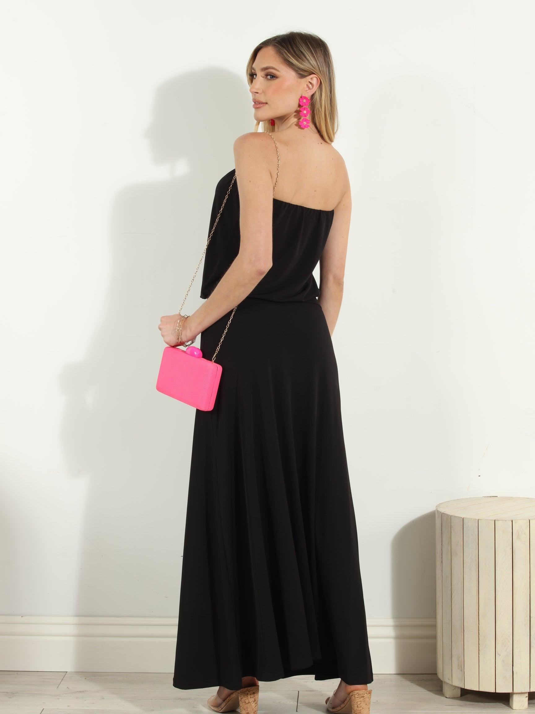 back side of black strapless maxi dress on woman holding pink purse