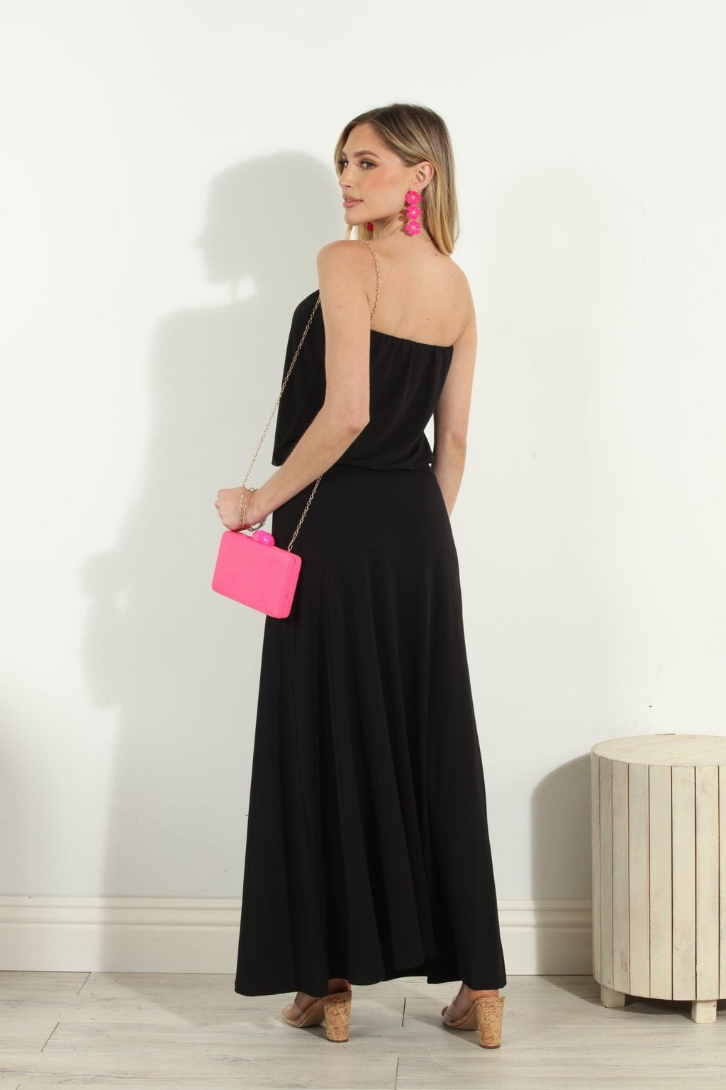back side of black strapless maxi dress on woman holding pink purse