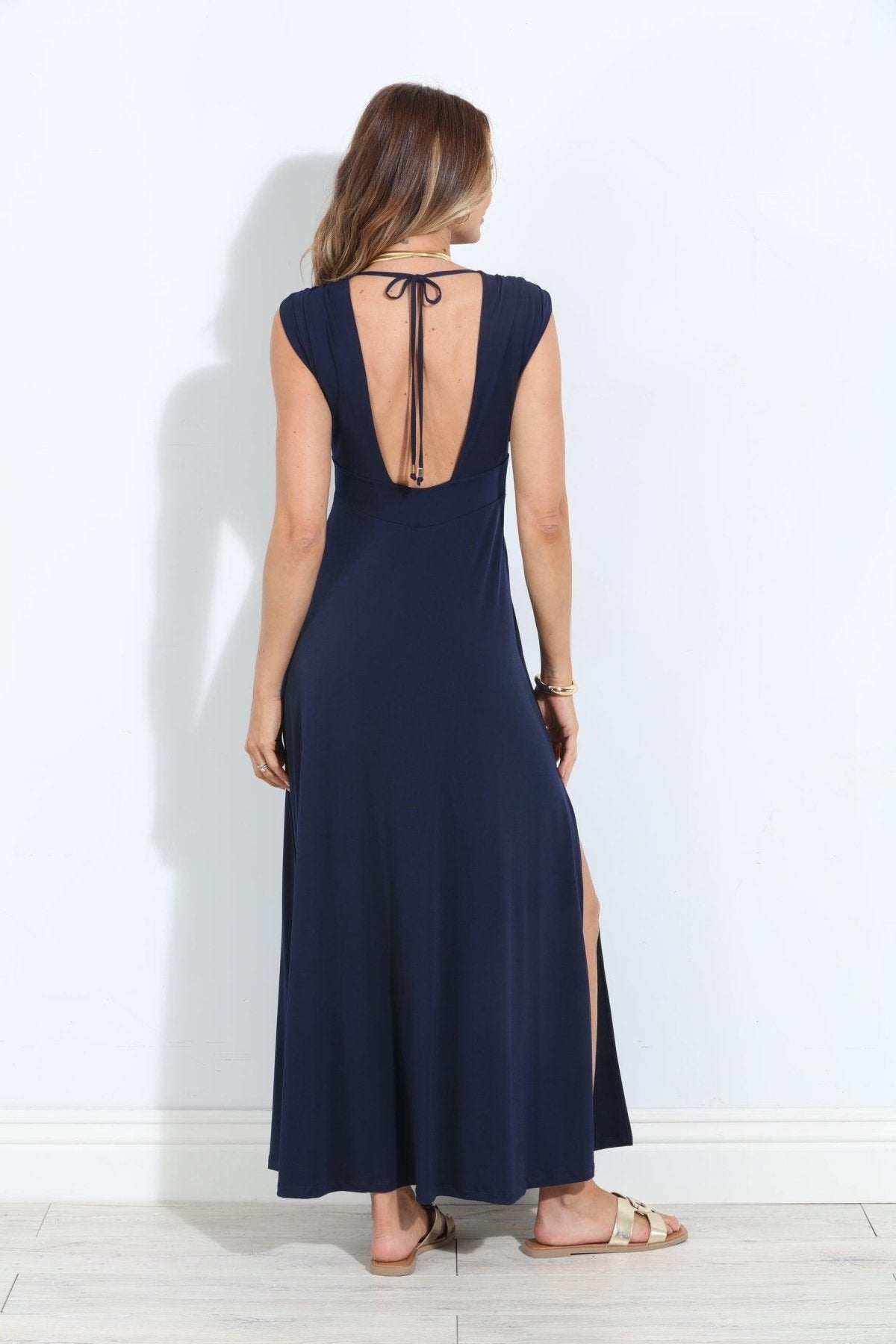 back side of navy sleeveless maxi dress with deep neckline and side slit on woman