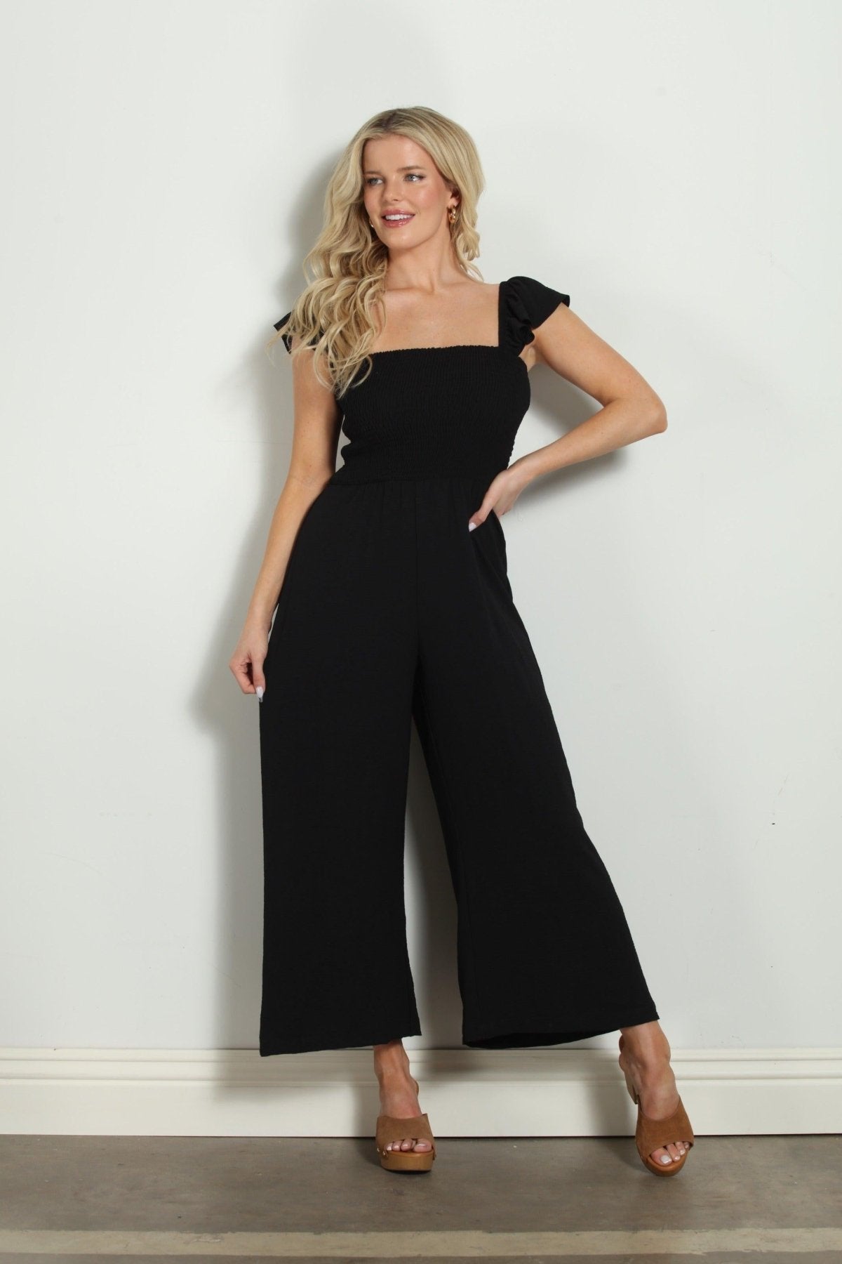 black sleeveless jumpsuit styled on woman in tan colored heels