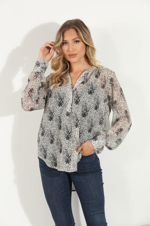 white and black printed long sleeve blouse on woman in denim pants