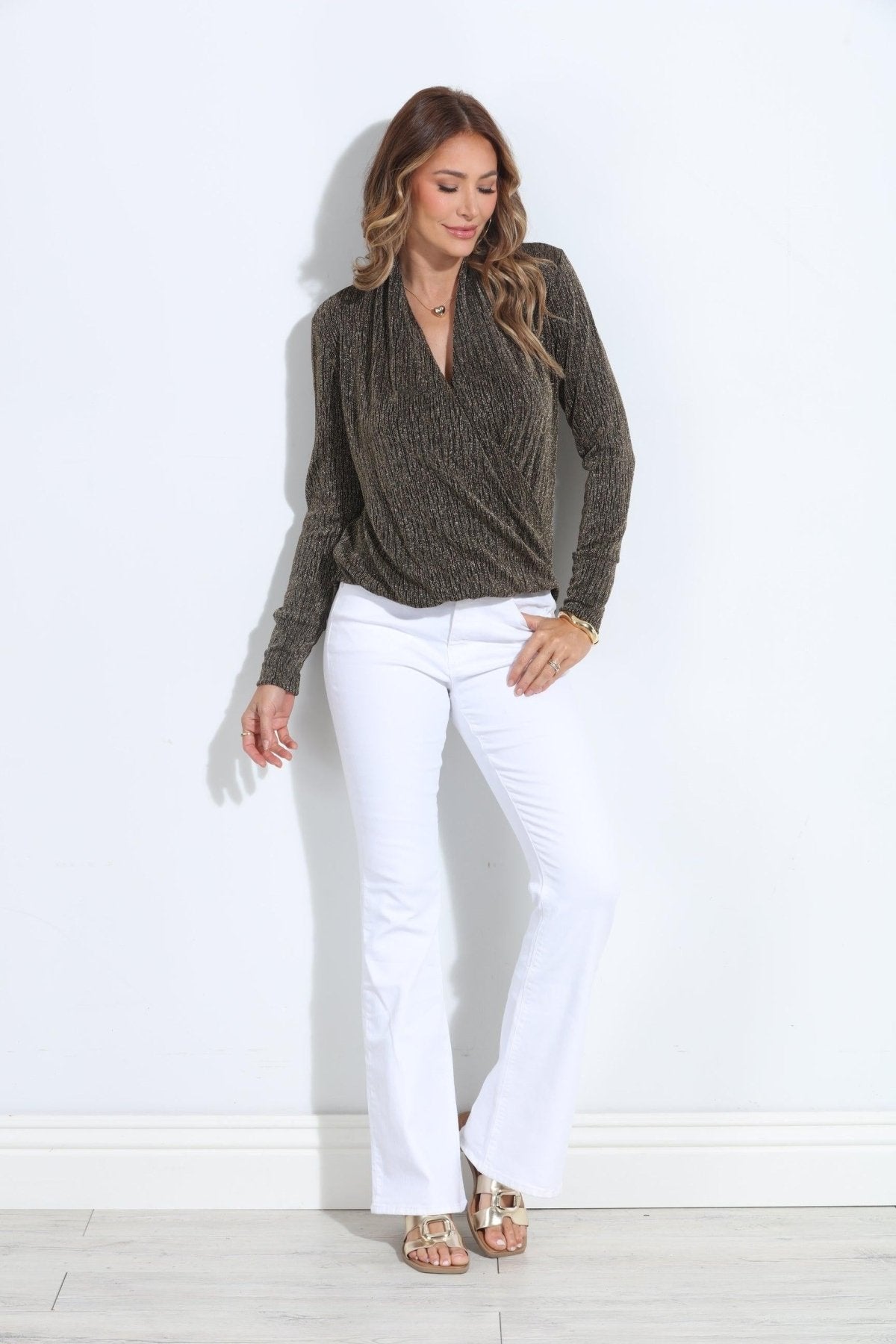 black and gold long sleeve top on woman in white pants and gold sandals
