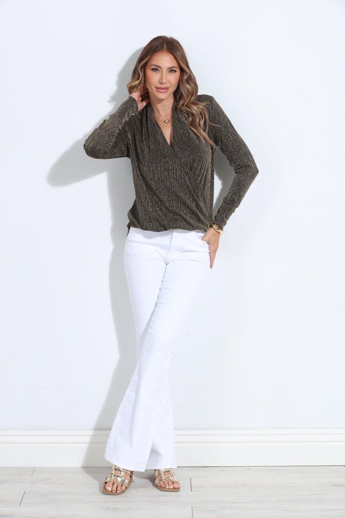 black and gold long sleeve top on woman in white pants and gold sandals