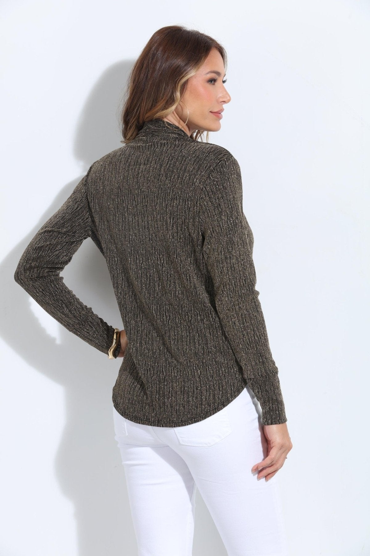 backside of black and gold long sleeve top on woman in white pants