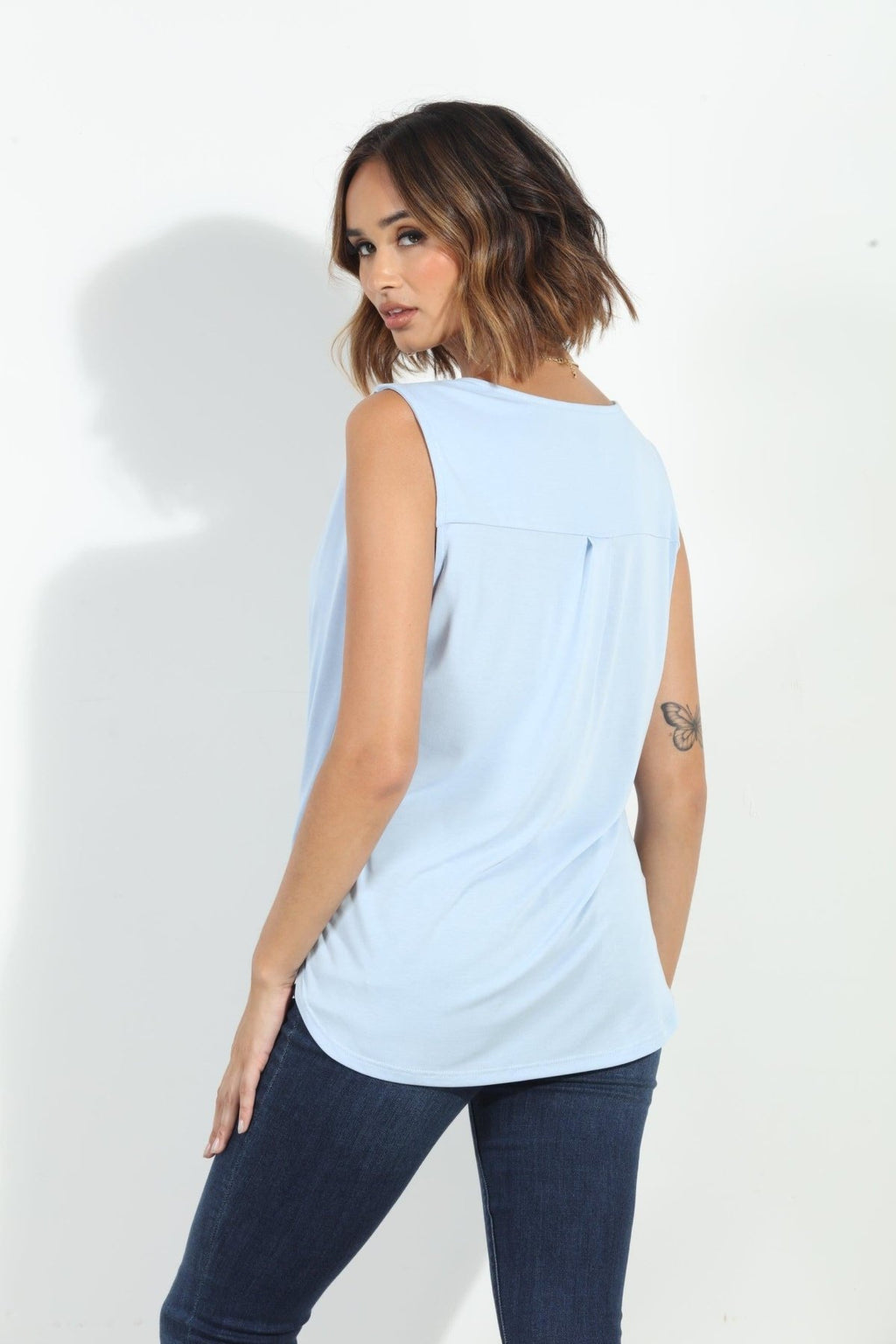 back side of light blue sleeveless top on woman in denim pants