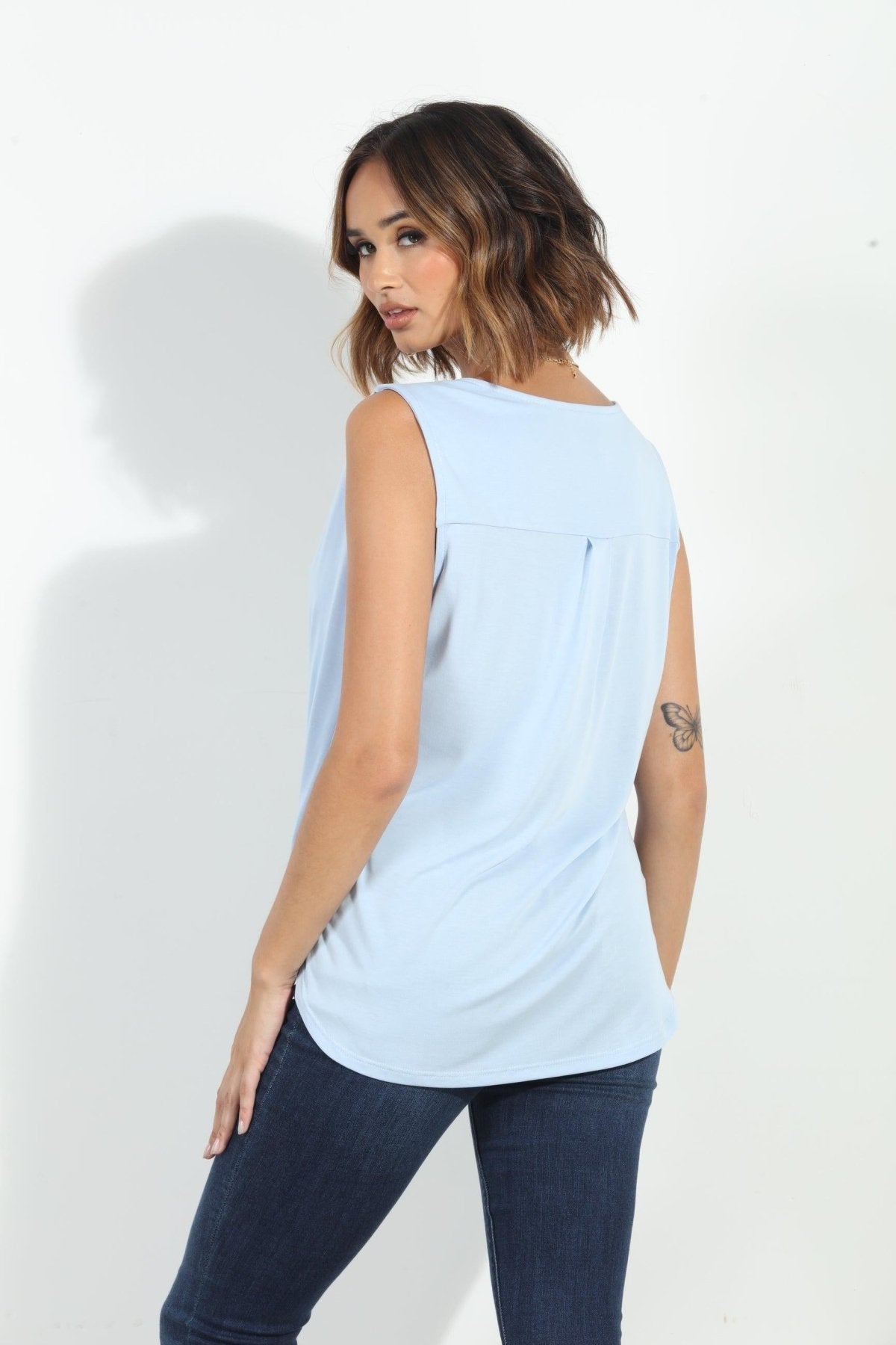 back side of light blue sleeveless top on woman in denim pants