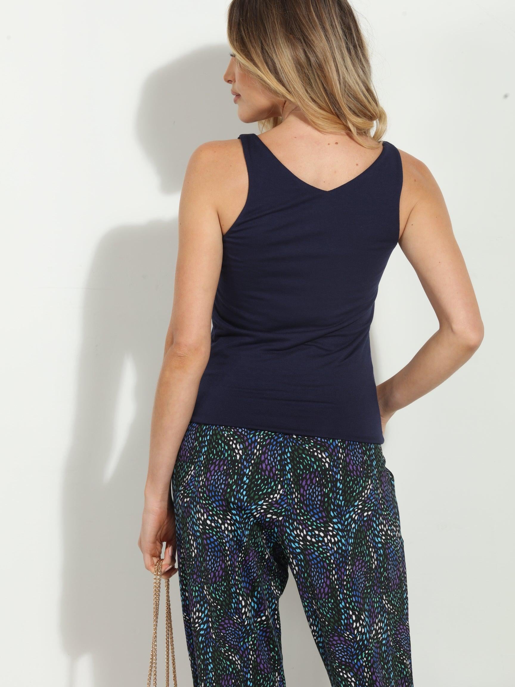 back side of navy sleeveless top on woman in multicolored pants