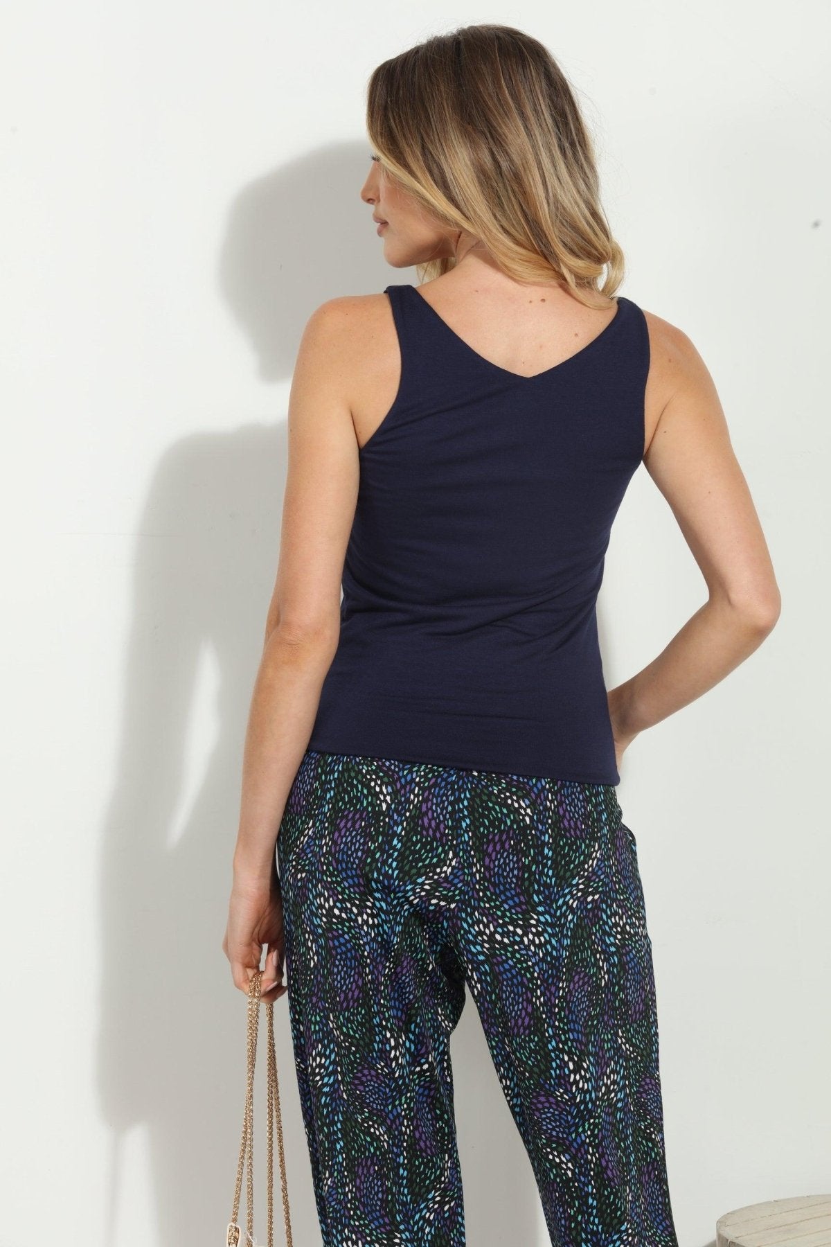 back side of navy sleeveless top on woman in multicolored pants