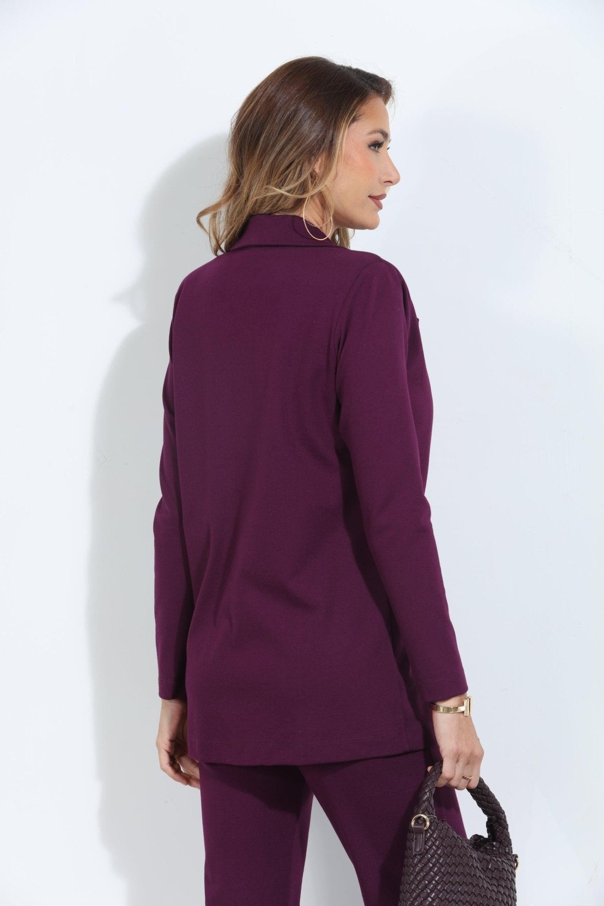 back side of dark purple blazer and pant set on woman holding deep purple purse